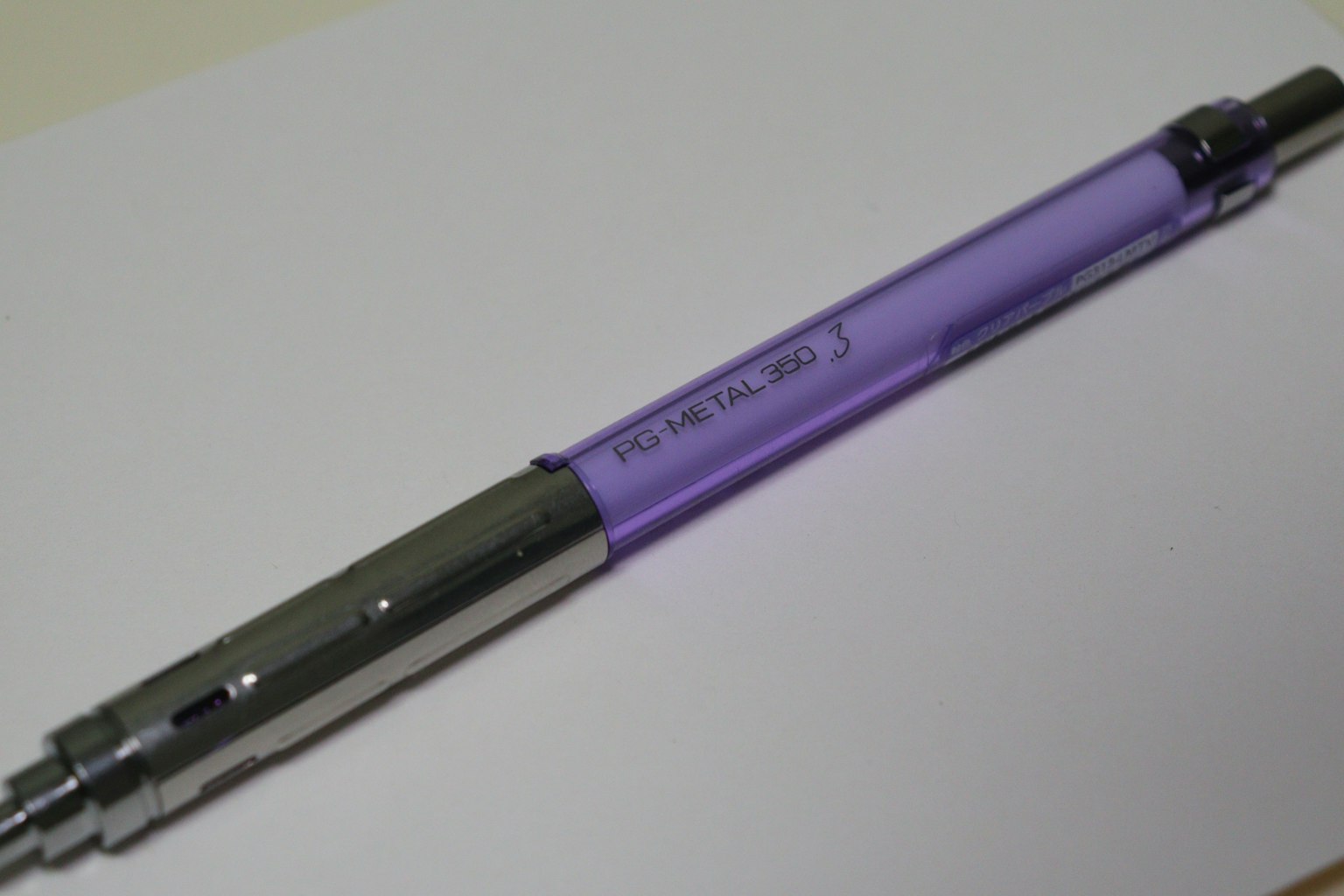 A purple ballpoint pen lying on a white sheet of paper