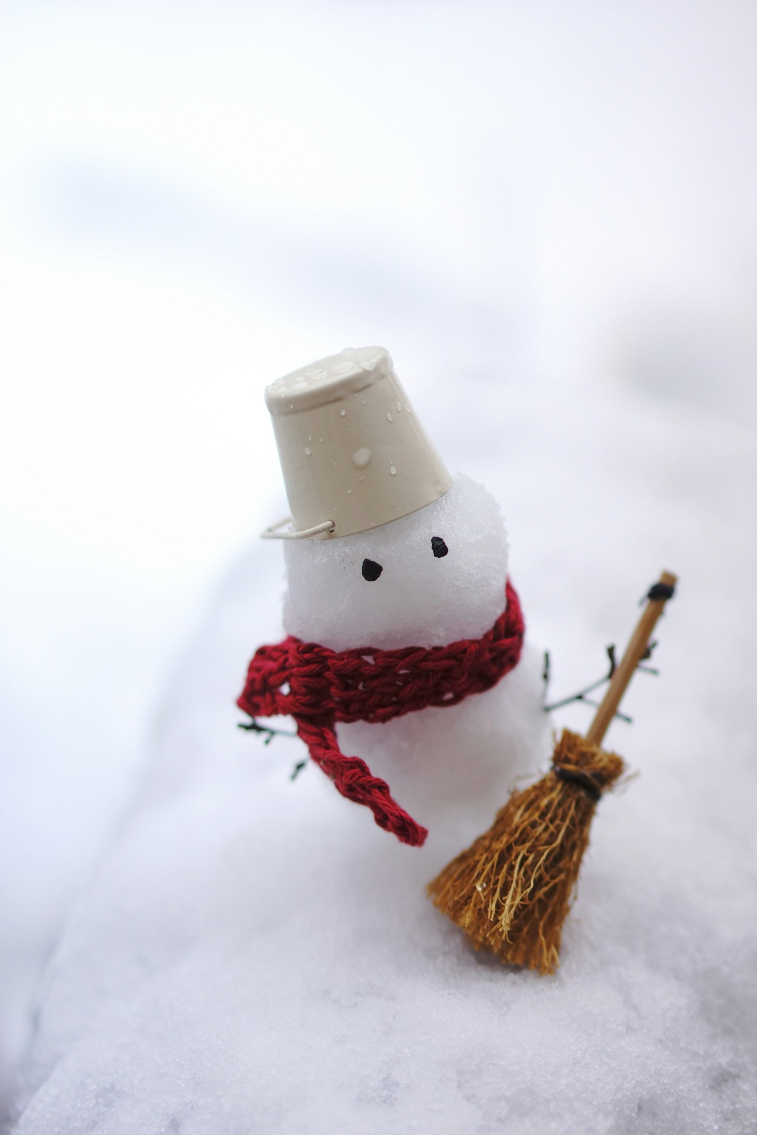 Ein Schneemann mit einem roten Schal und einem weißen Hut auf weißem Schnee