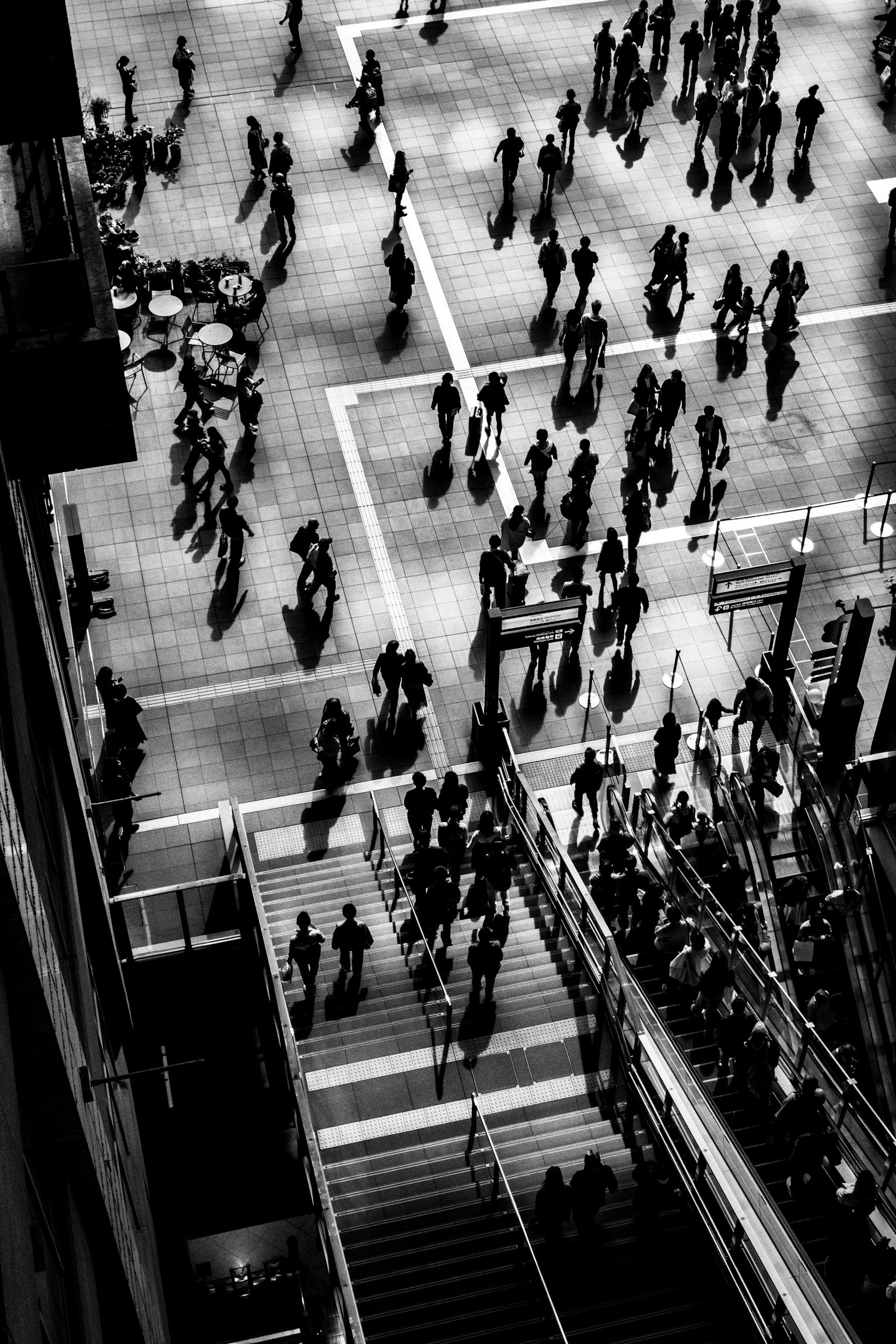 人々が行き交う都市の風景のモノクロ写真 階段と交差点が見える