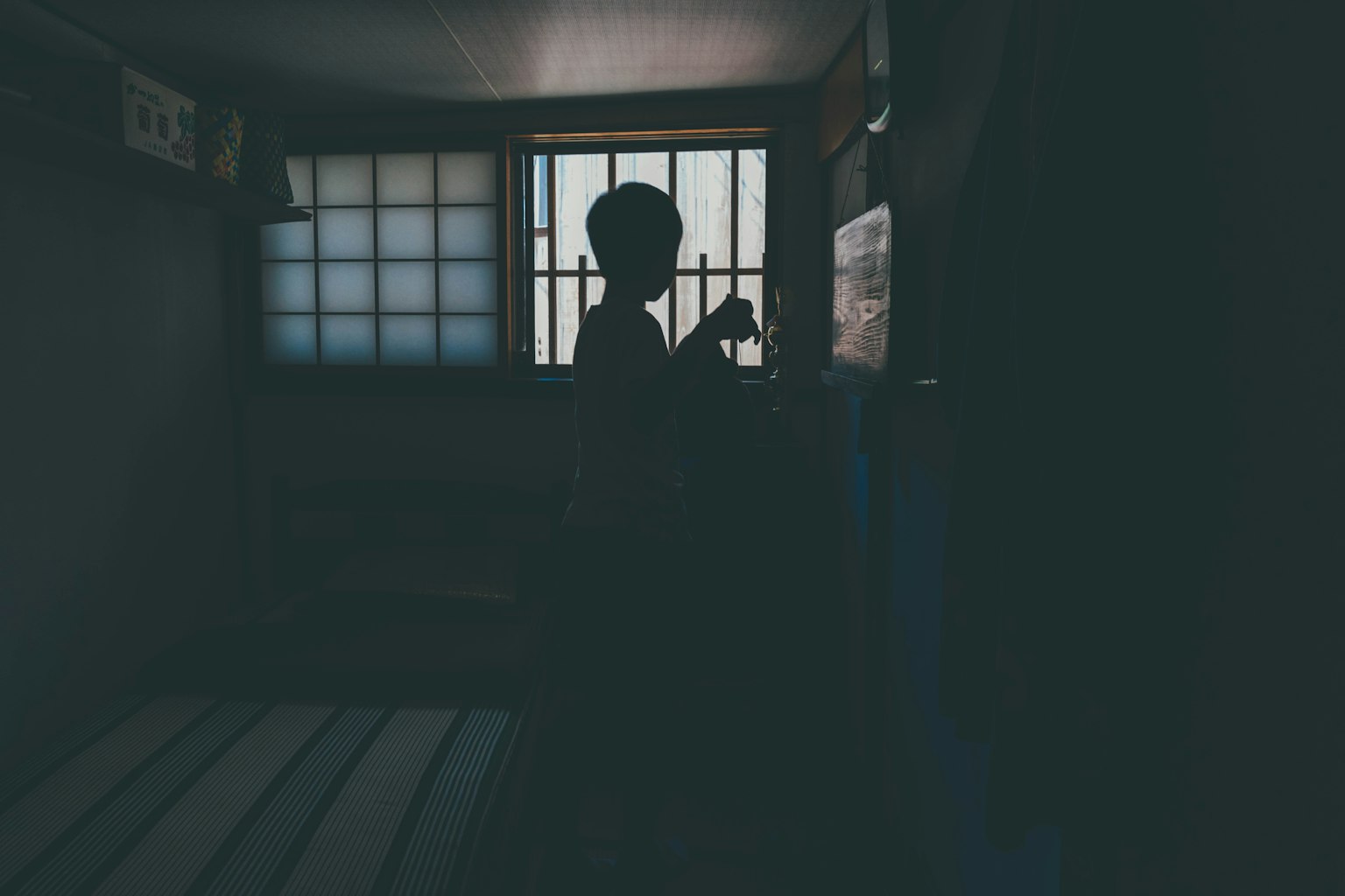 어두운 방의 창가에 서 있는 사람의 실루엣