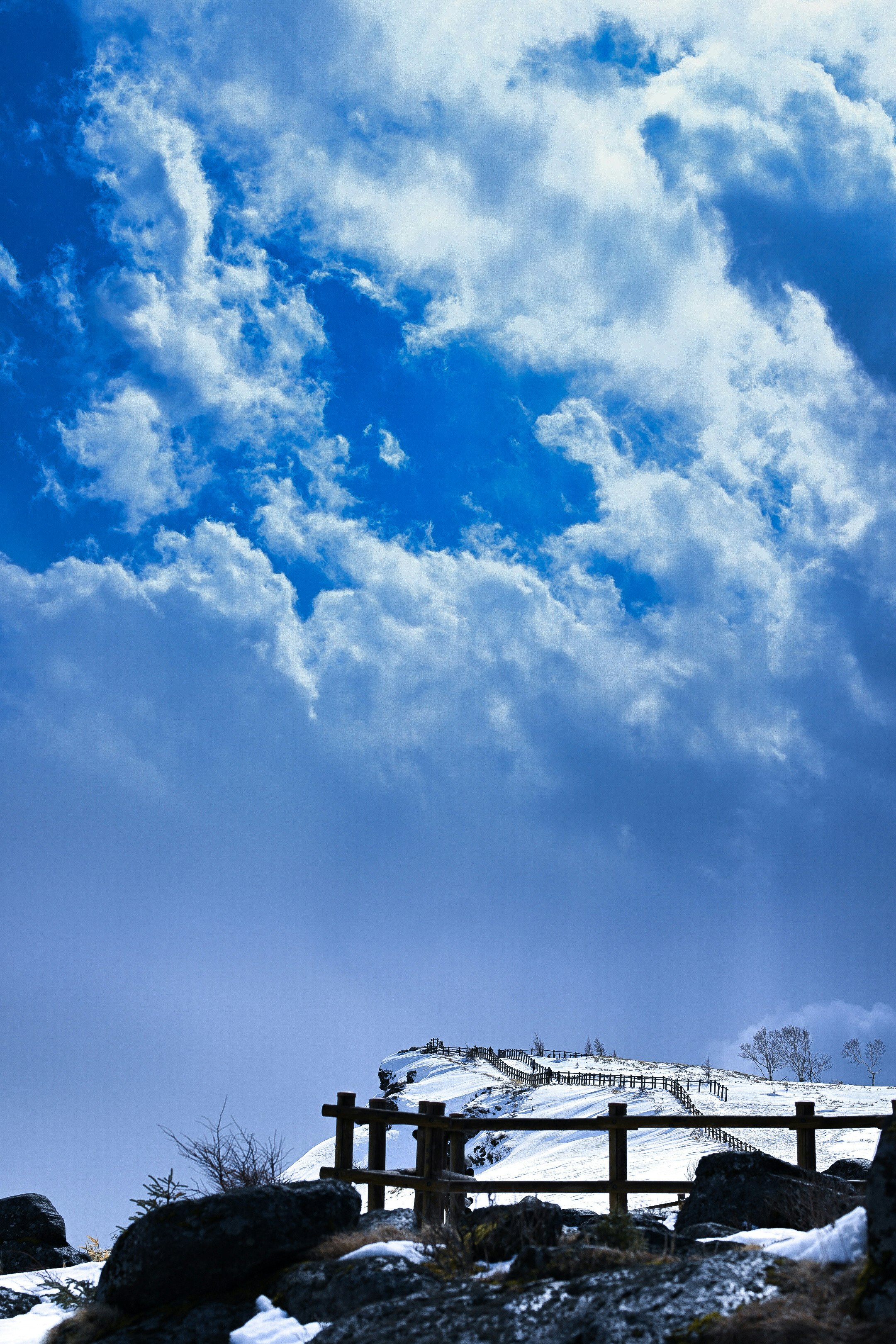 青空の下の雪の山並みと展望デッキ