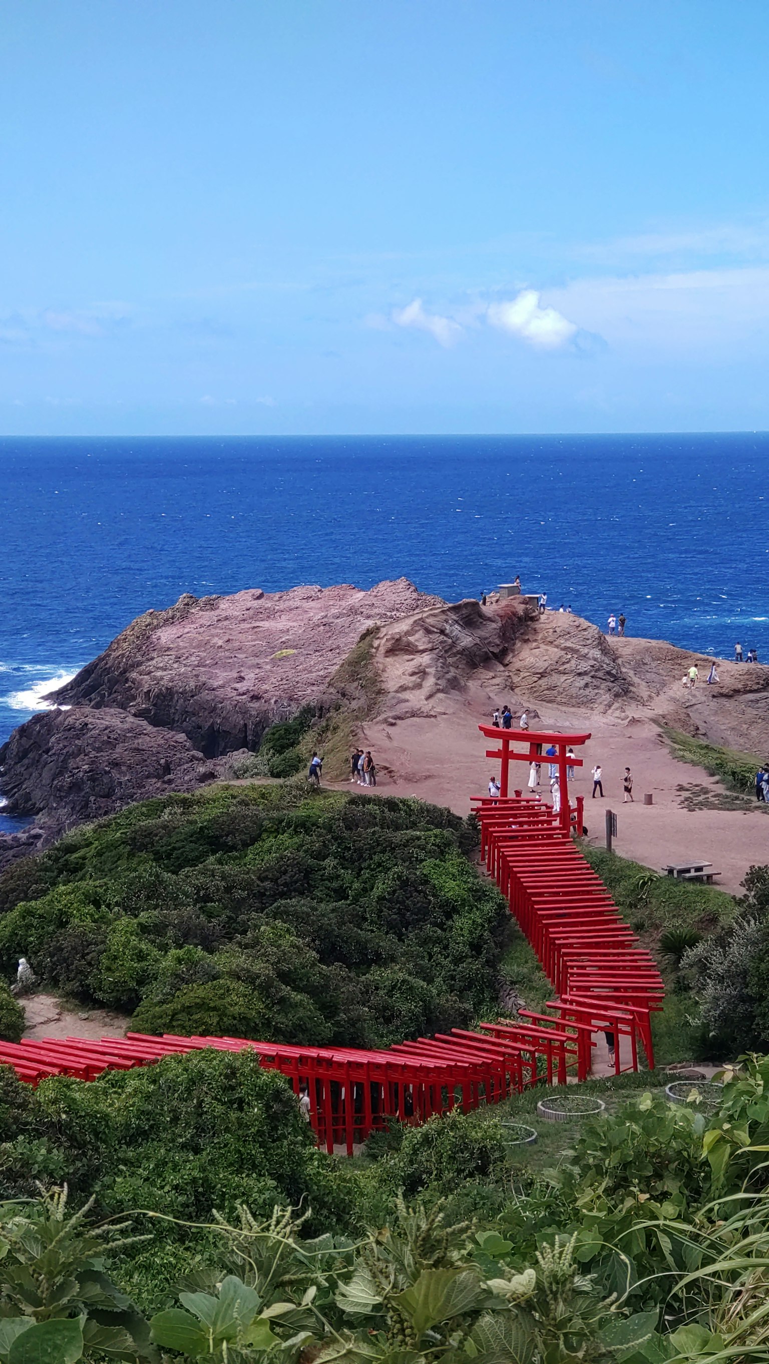Vista escénica de una puerta torii roja contra un océano azul