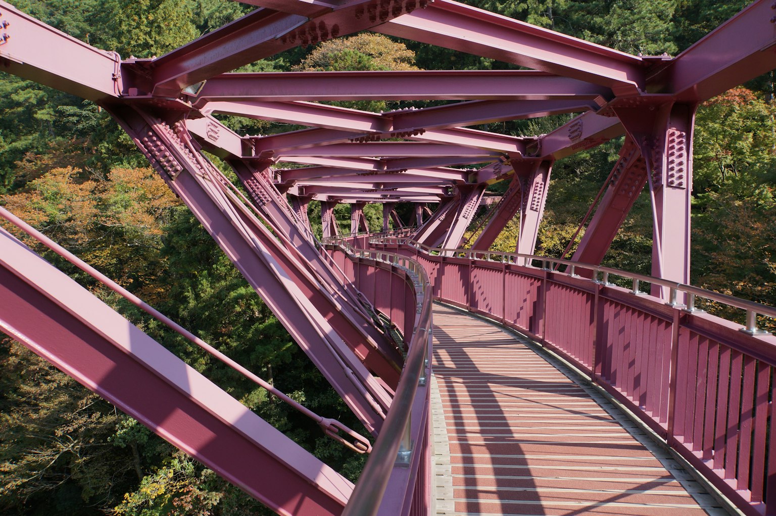A beautiful pink bridge spans a scenic landscape with intricate architecture