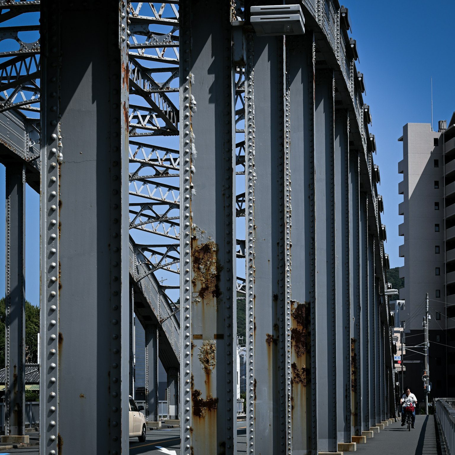 Old iron bridge structure with pedestrians under blue sky