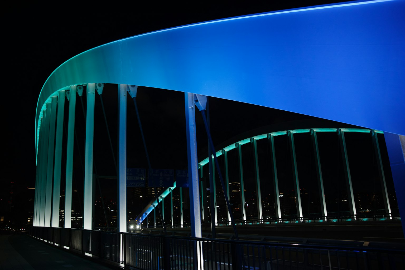 สะพานโค้งที่มีแสงสีฟ้าและสีเขียวในเวลากลางคืน