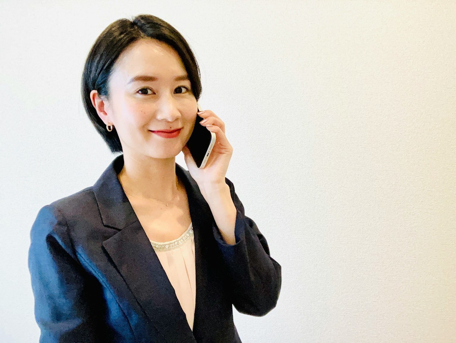 Eine Frau im Business-Anzug, die mit einem Smartphone spricht