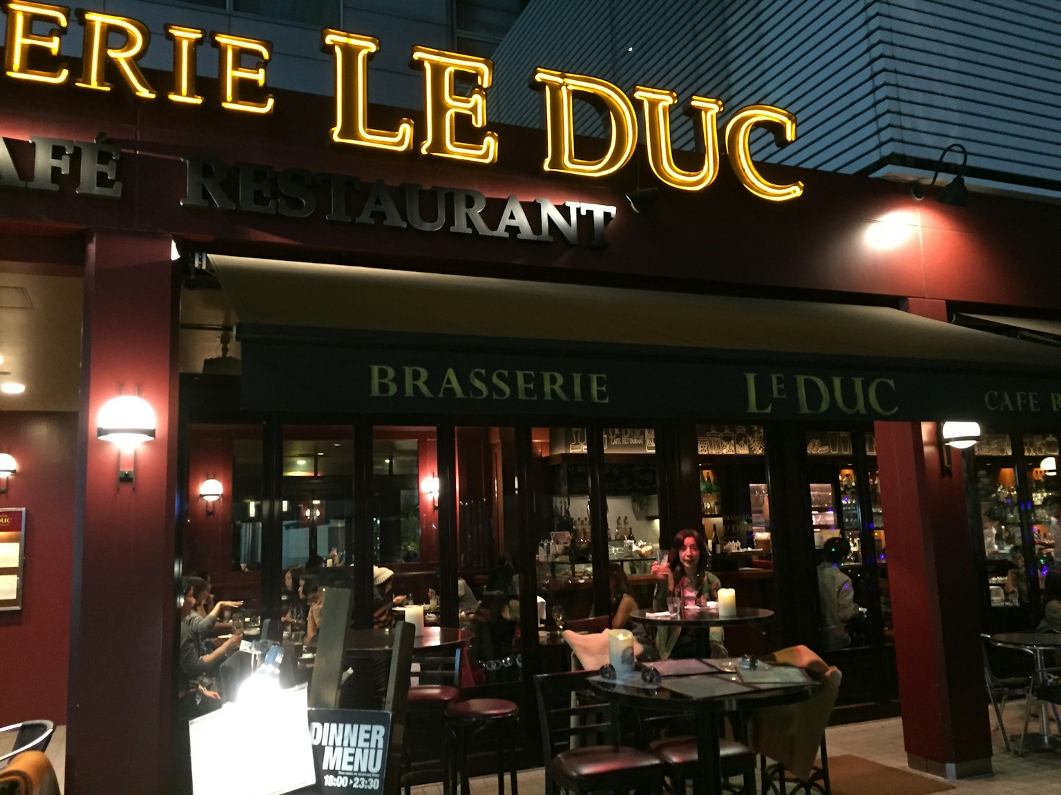 Ngoại thất Brasserie Le Duc với biển hiệu sáng và bàn kiểu quán cà phê