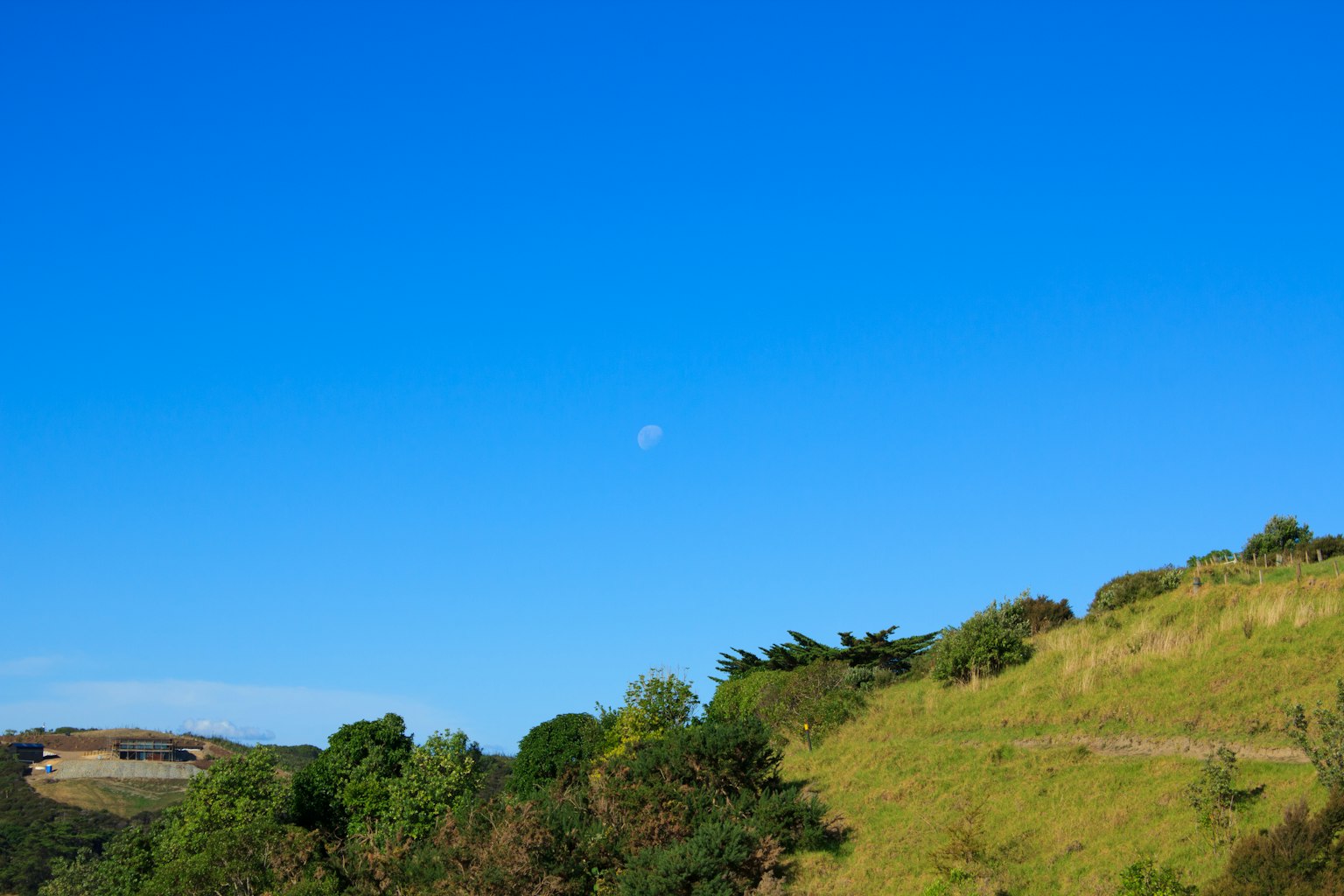 Lune dans un ciel bleu clair au-dessus des collines vertes