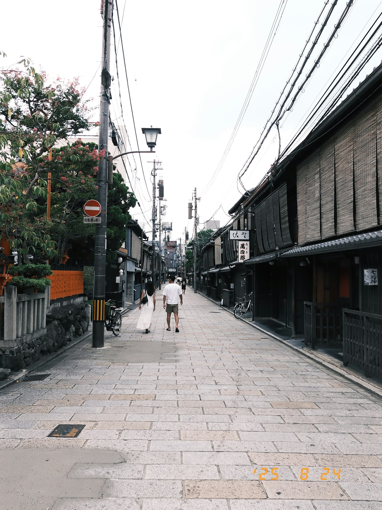 静かな街並みの通りに人が歩いている風景 古い建物と電線が見える
