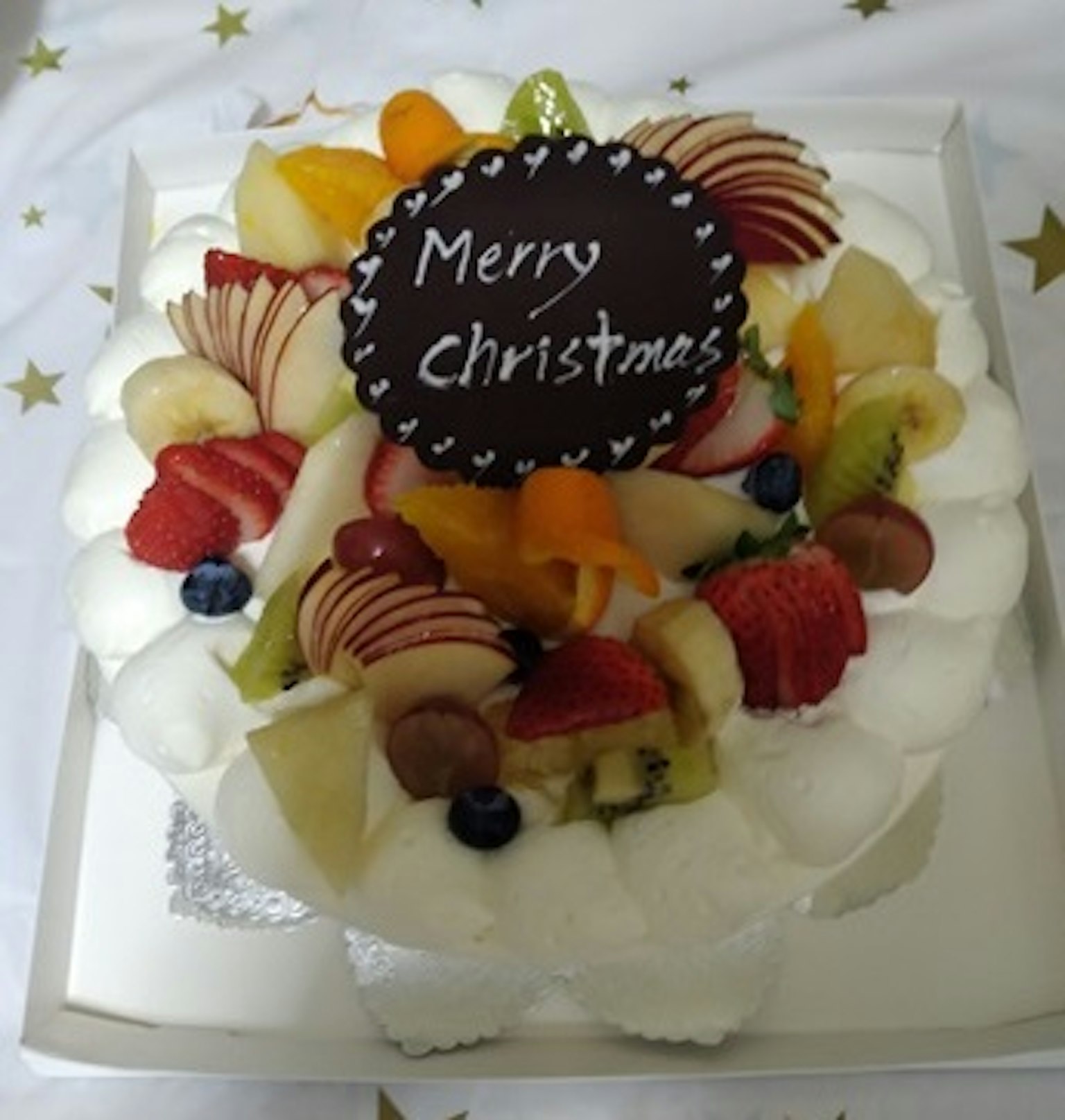 Obstkuchen dekoriert mit einer Frohe Weihnachten Nachricht und verschiedenen Früchten