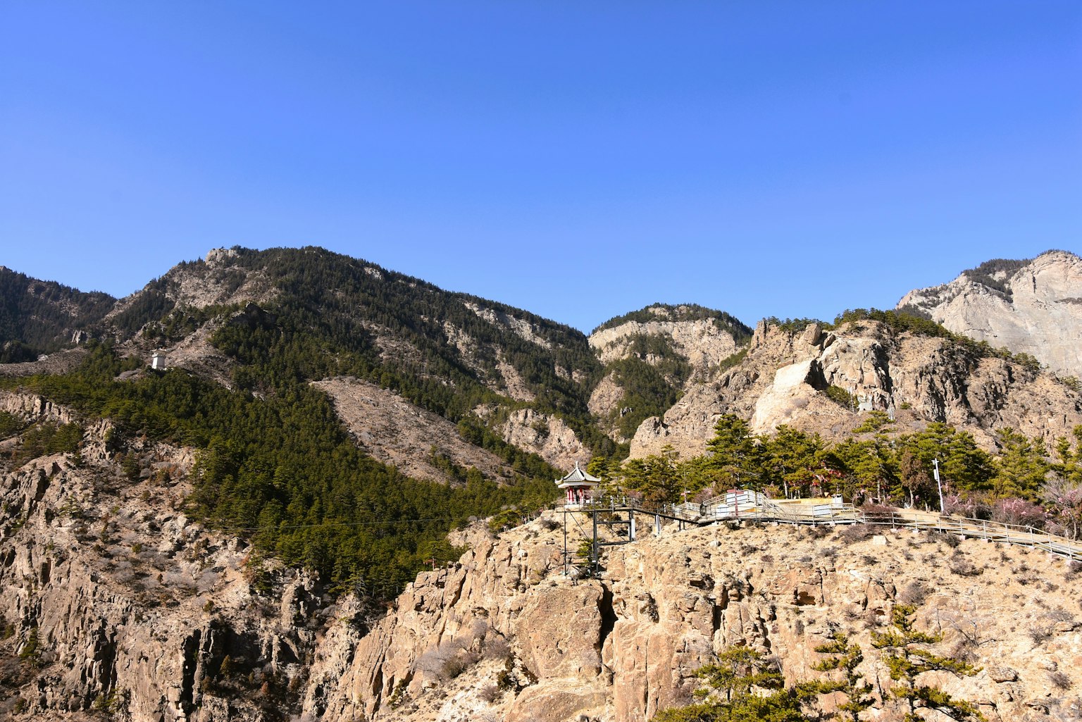 Paisaje escénico con cielo azul y montañas terreno rocoso con árboles verdes