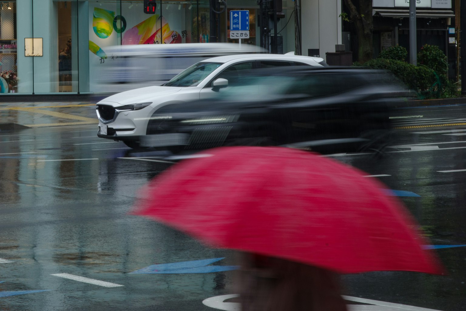 雨中行驶的汽车与一位拿着红伞的人