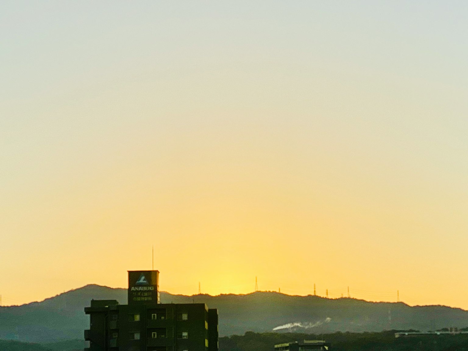 Tramonto dietro le montagne con un edificio in primo piano