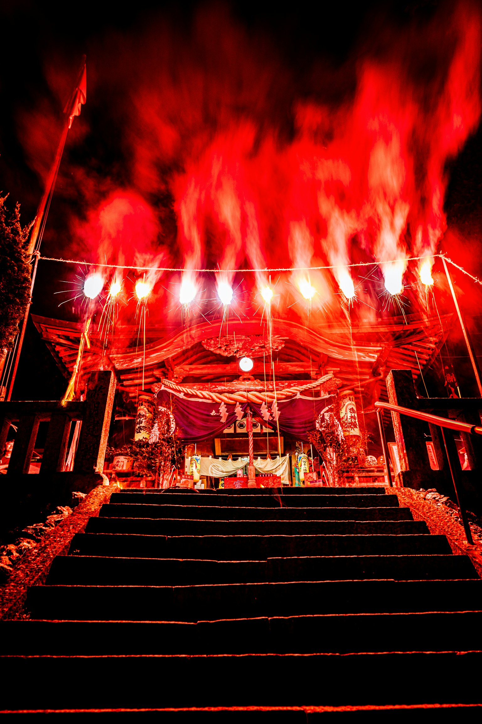 赤い煙と明るい照明が特徴の神社の階段