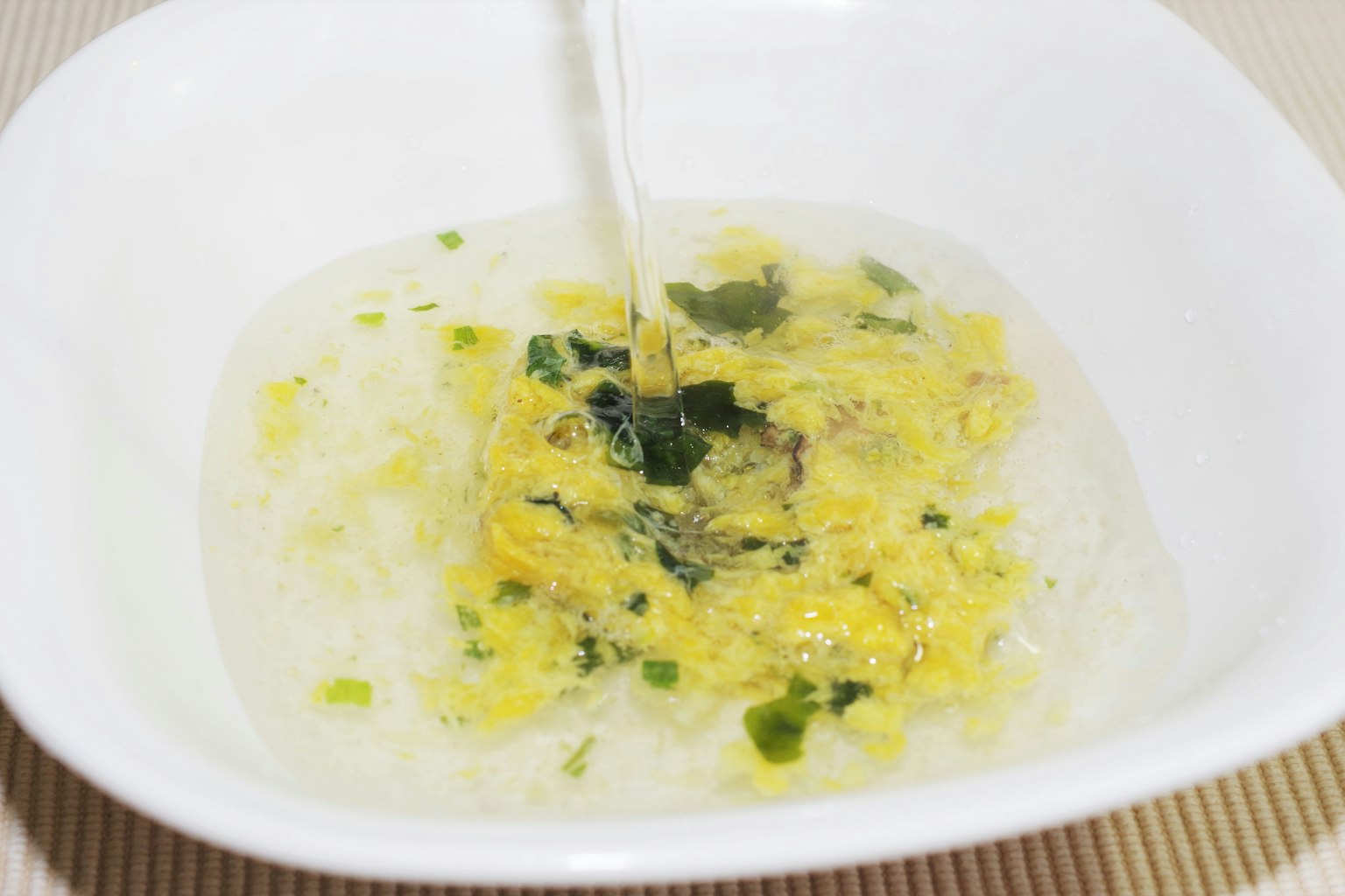 Bowl of soup with mixed eggs and greens