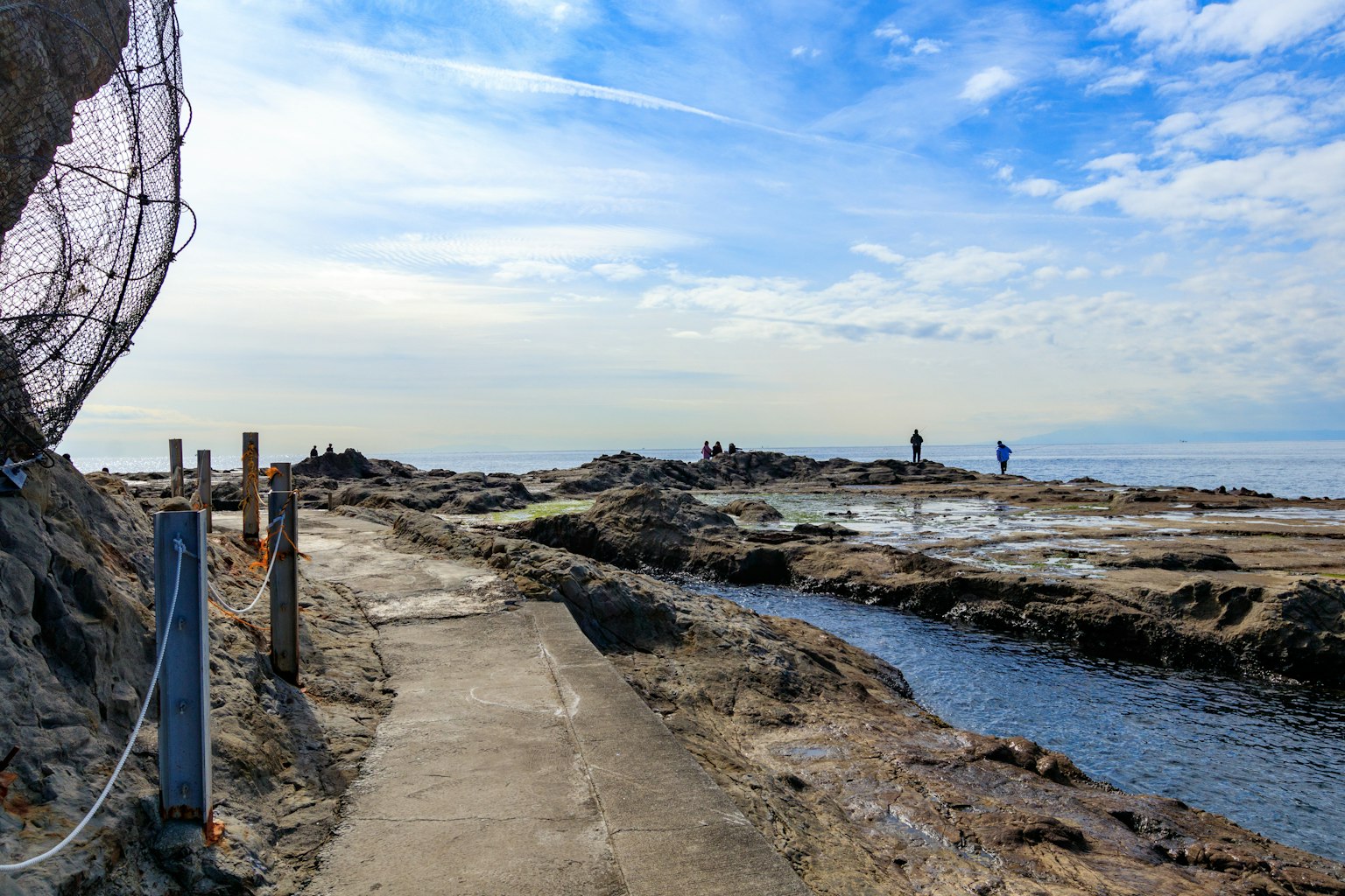 Jalan pesisir di sepanjang pantai berbatu dengan langit biru