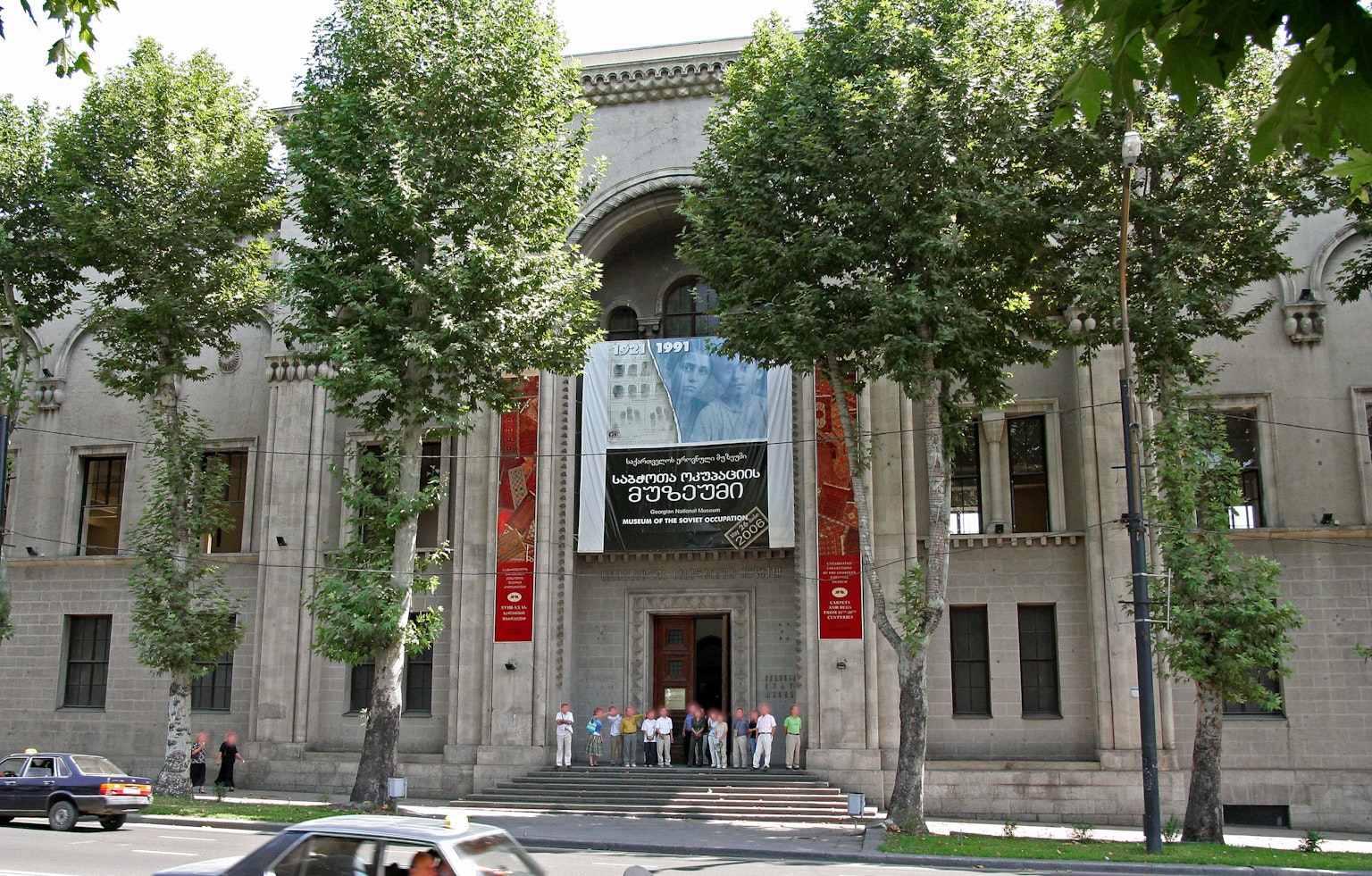 The front of a building featuring a large banner and people gathered outside