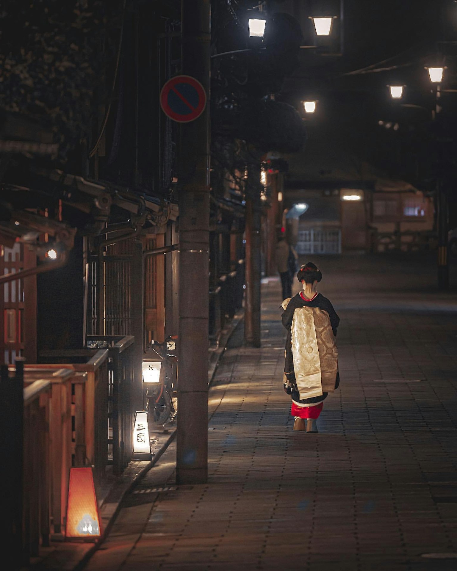 밤에 조명이 켜진 거리를 걷고 있는 기모노를 입은 여성