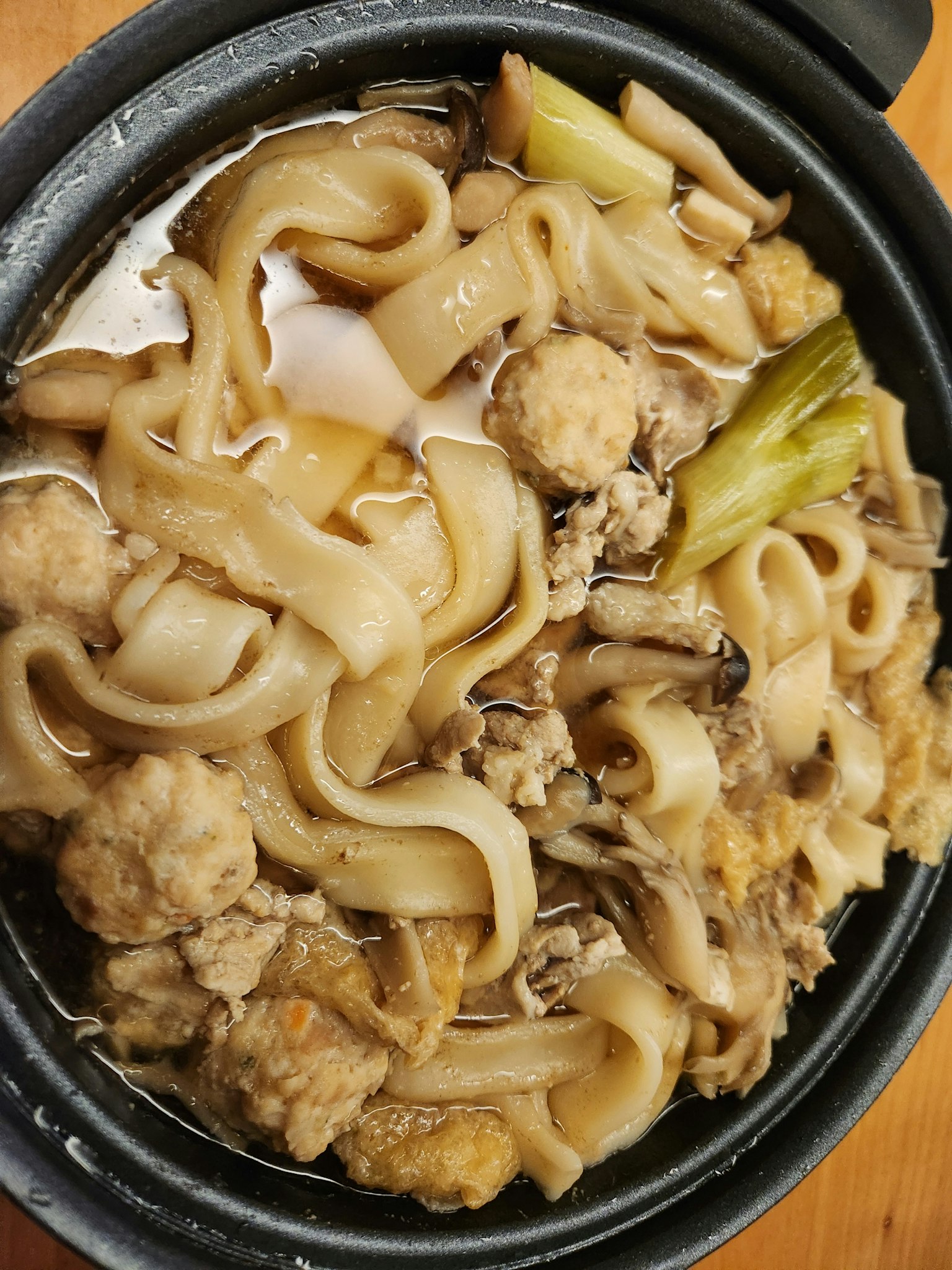Panci hangat penuh dengan mie udon dan bakso