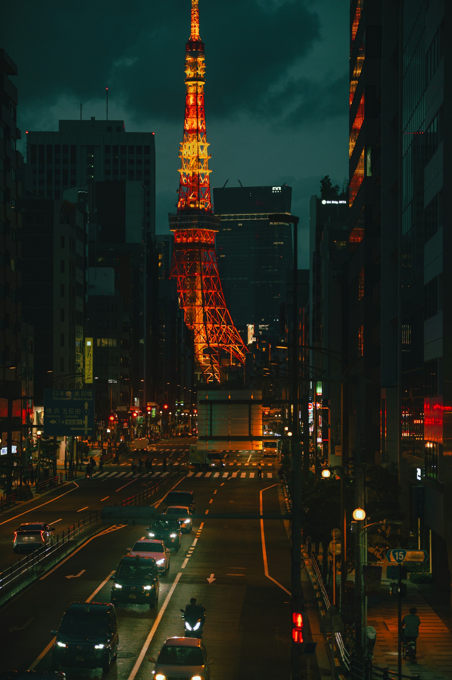 Tokyo Tower illuminated at night with a bustling street and cars