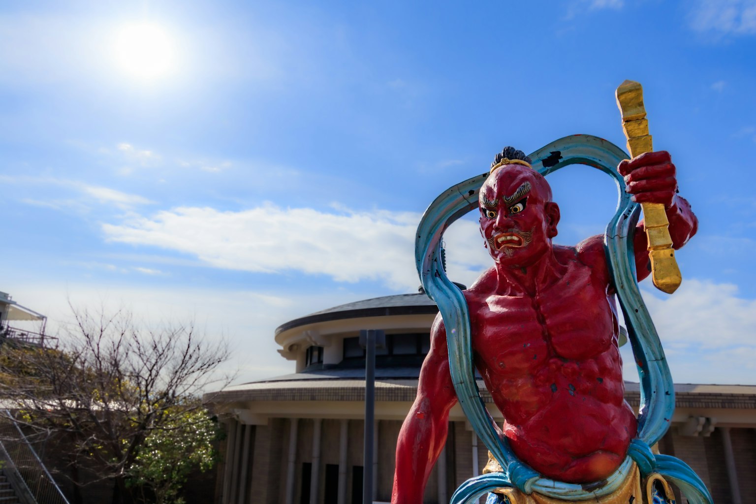 Una estatua de demonio rojo se encuentra bajo un cielo azul