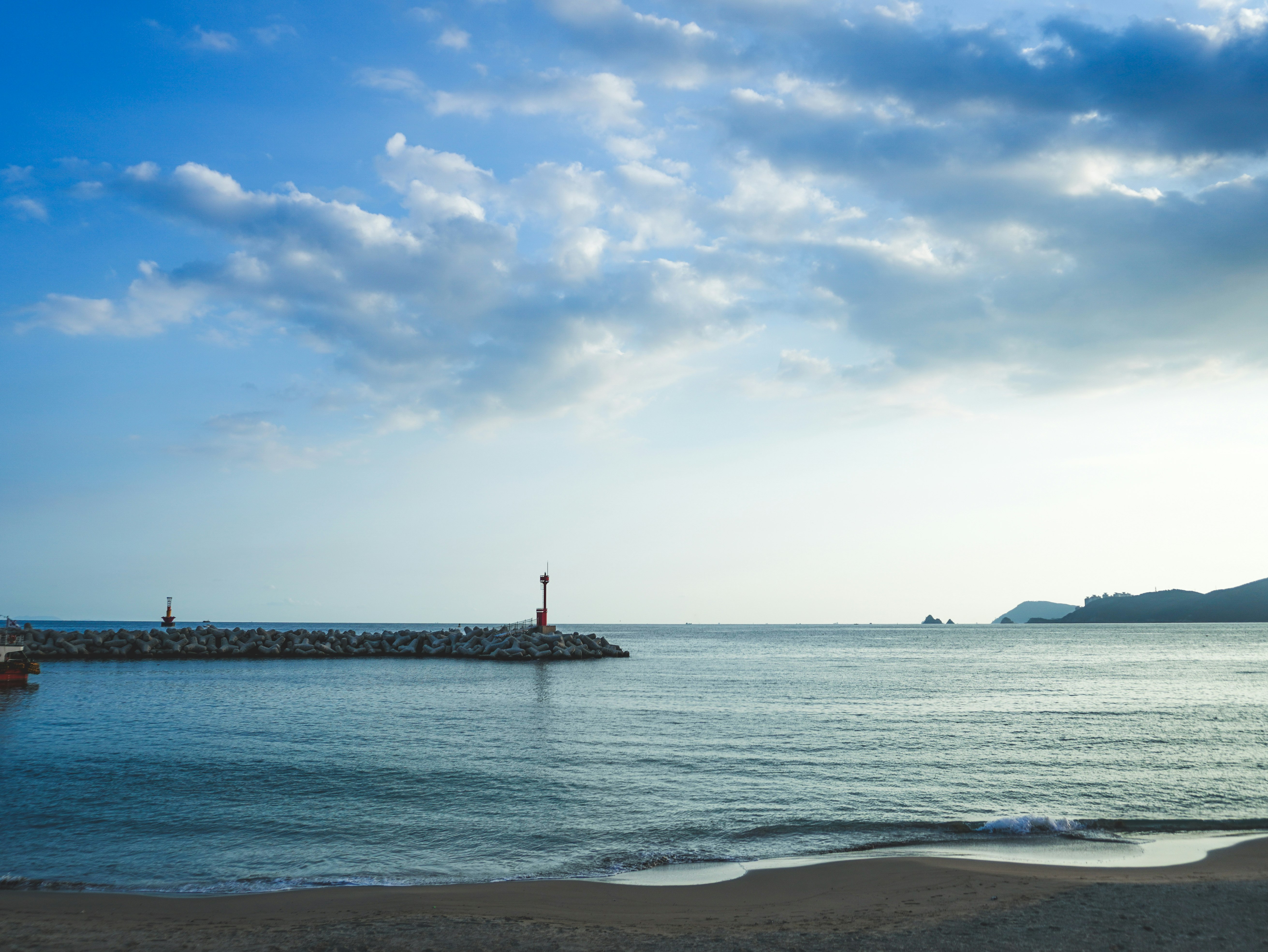 海辺の砂浜と沖合の灯台が見える海景