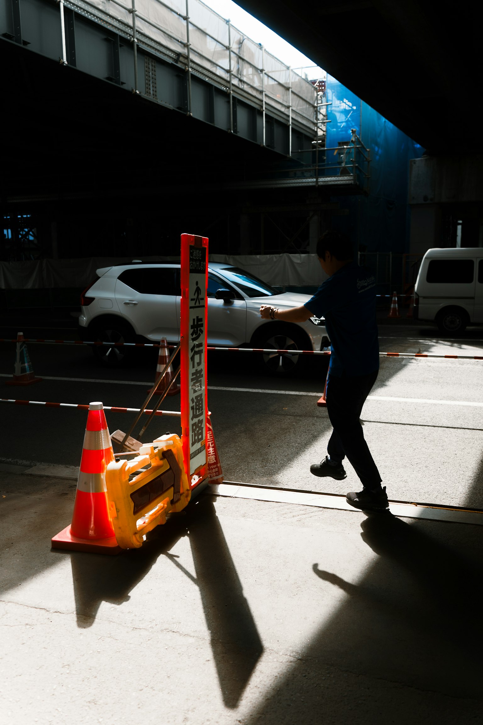Scène urbaine avec un ouvrier de construction marchant près des cônes de circulation