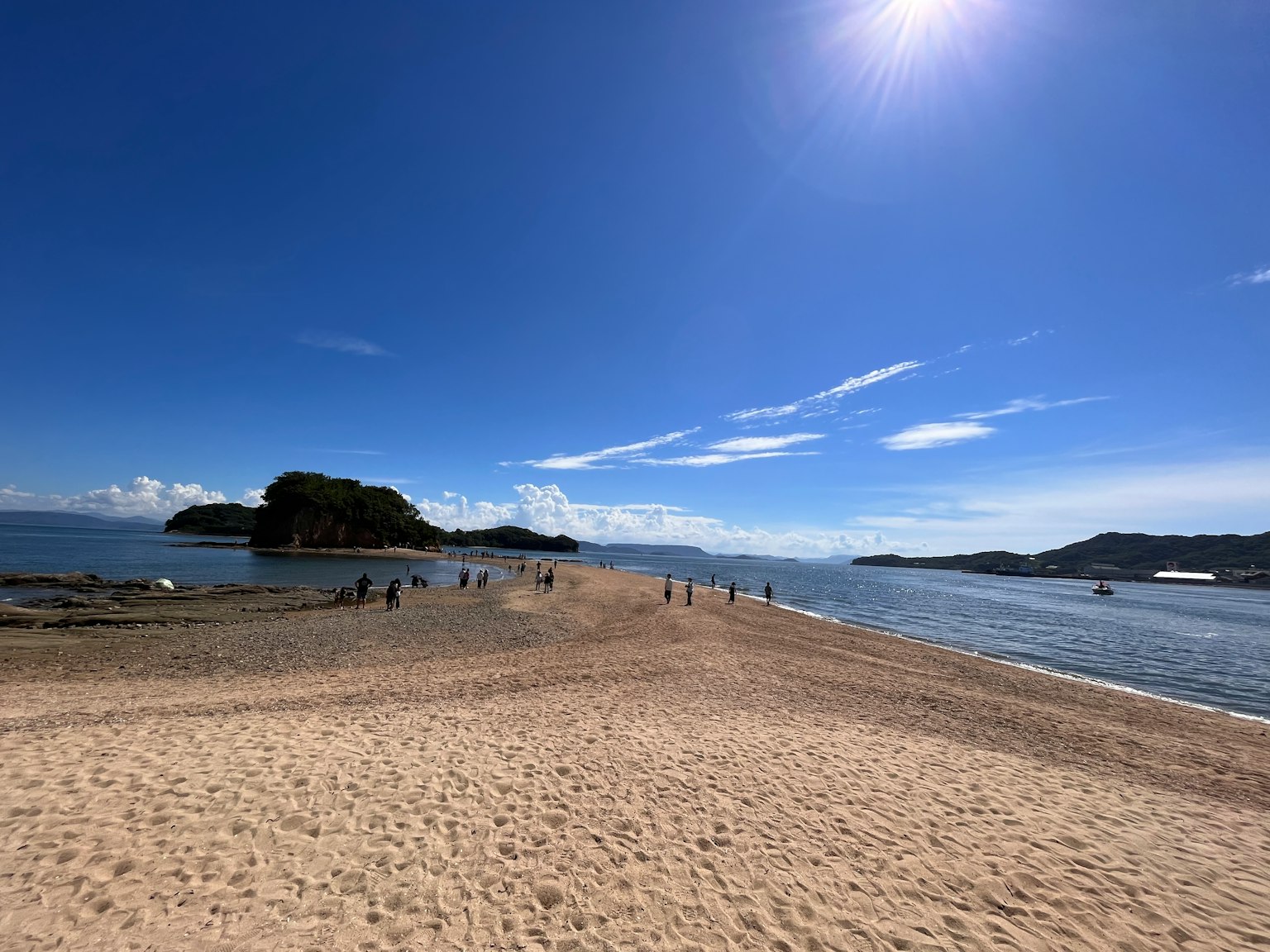 Escena de playa con cielo azul y océano personas caminando por la arena