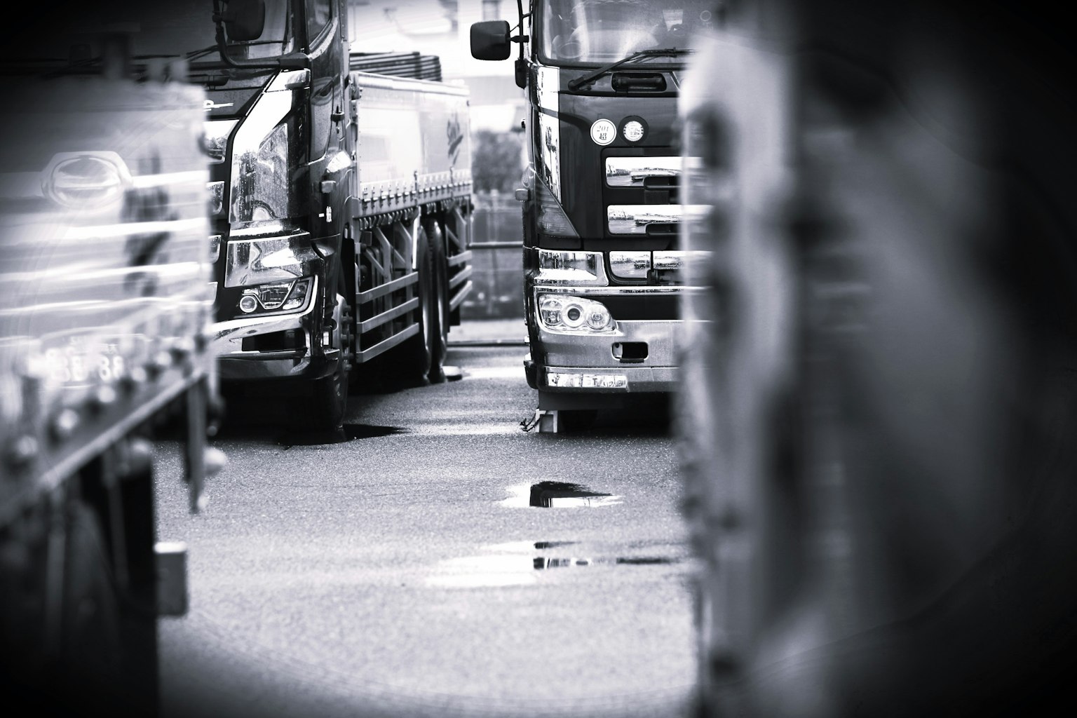 ภาพขาวดำของรถบรรทุกเรียงรายอยู่บนถนนพร้อมกับพื้นผิวที่มองเห็นได้