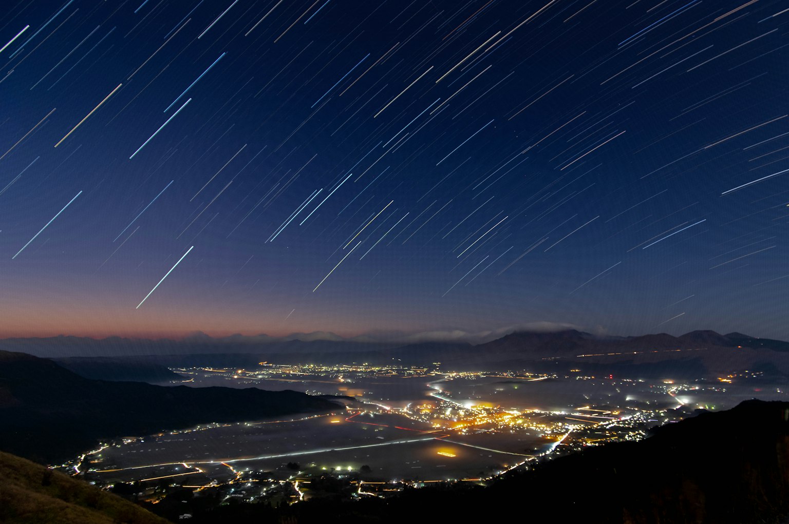 Paysage urbain sous un ciel nocturne avec des traînées d'étoiles