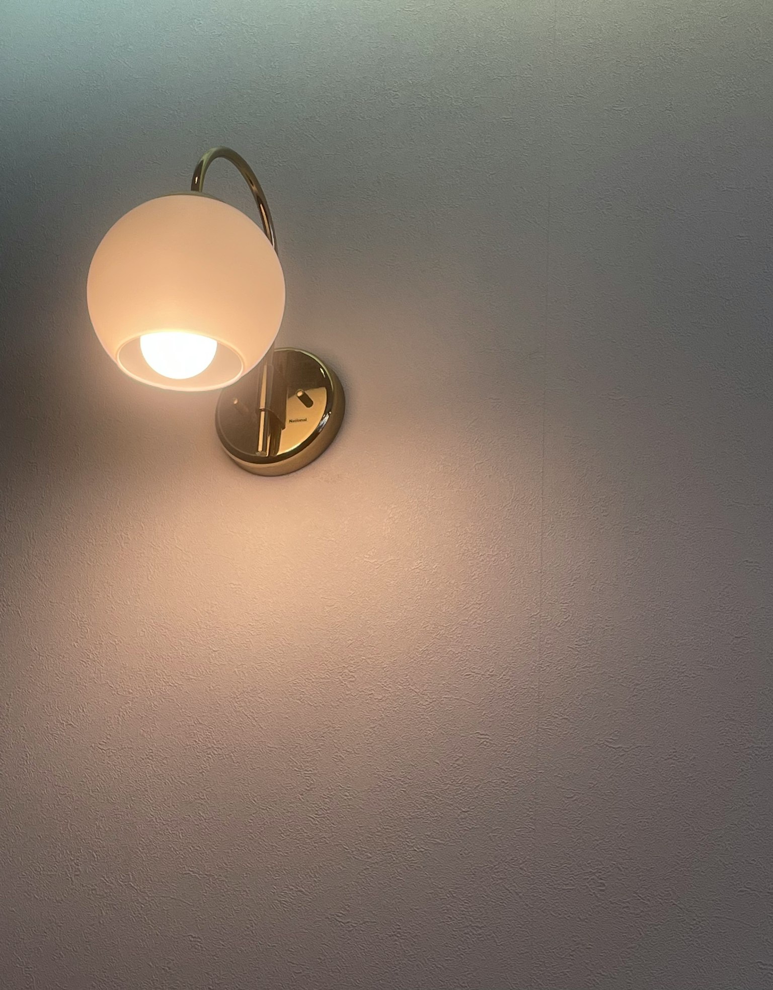 Un semplice apparecchio di illuminazione a parete con una shade sferica bianca