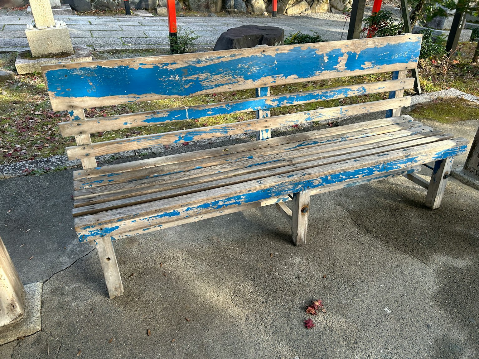 Old blue bench placed on a paved surface in a park