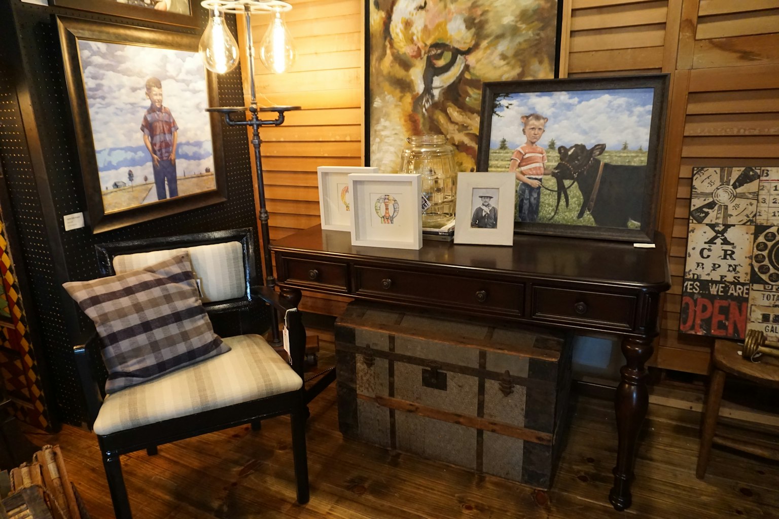 Scena interna con tavolo in legno e sedia con dipinti e fotografie appesi al muro