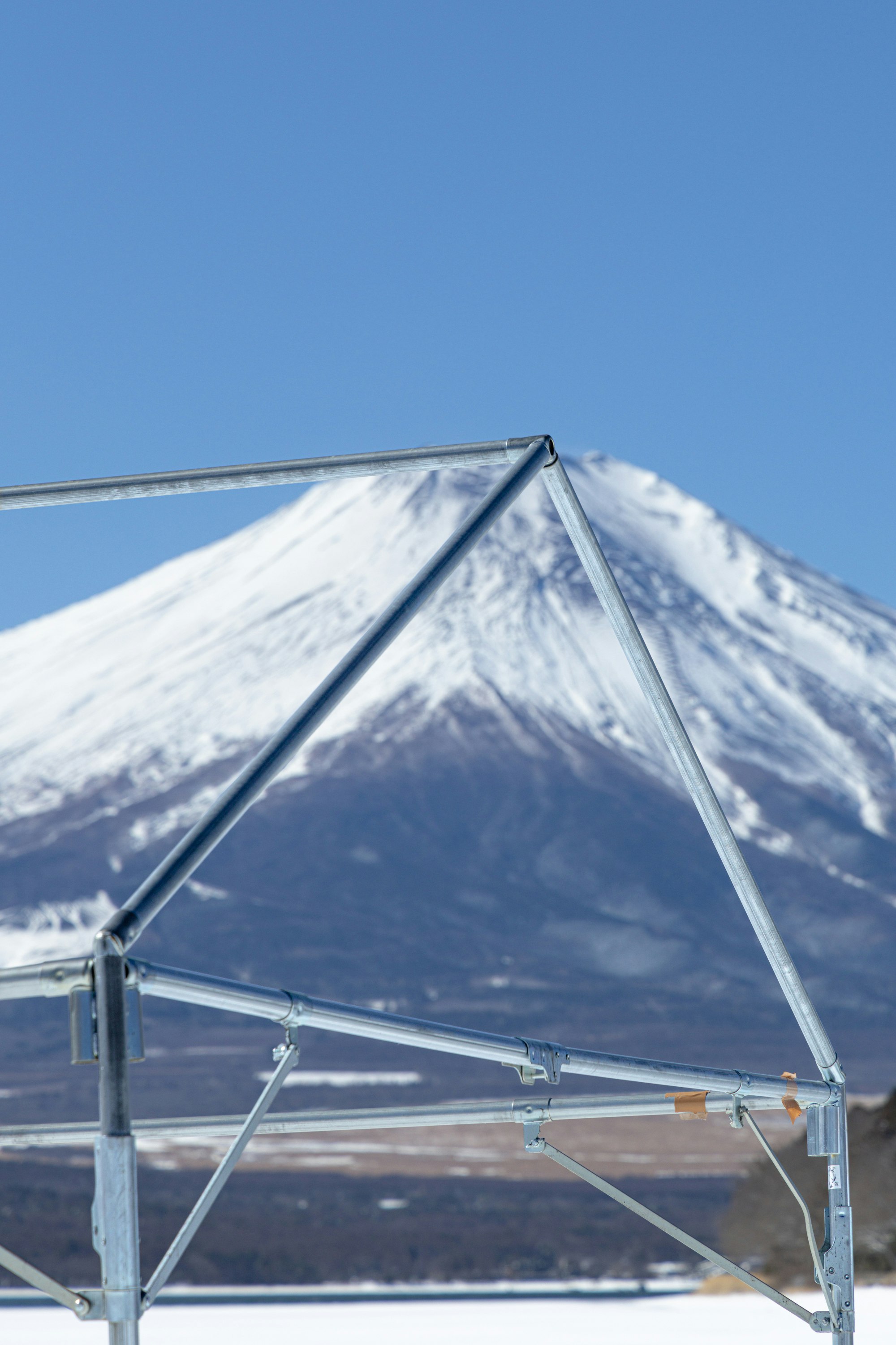 青空の下にそびえる雪をかぶった山と山小屋のようなテント