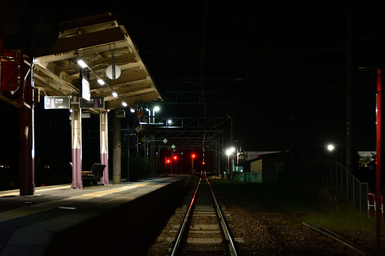Vista notturna di una piattaforma ferroviaria con binari illuminati