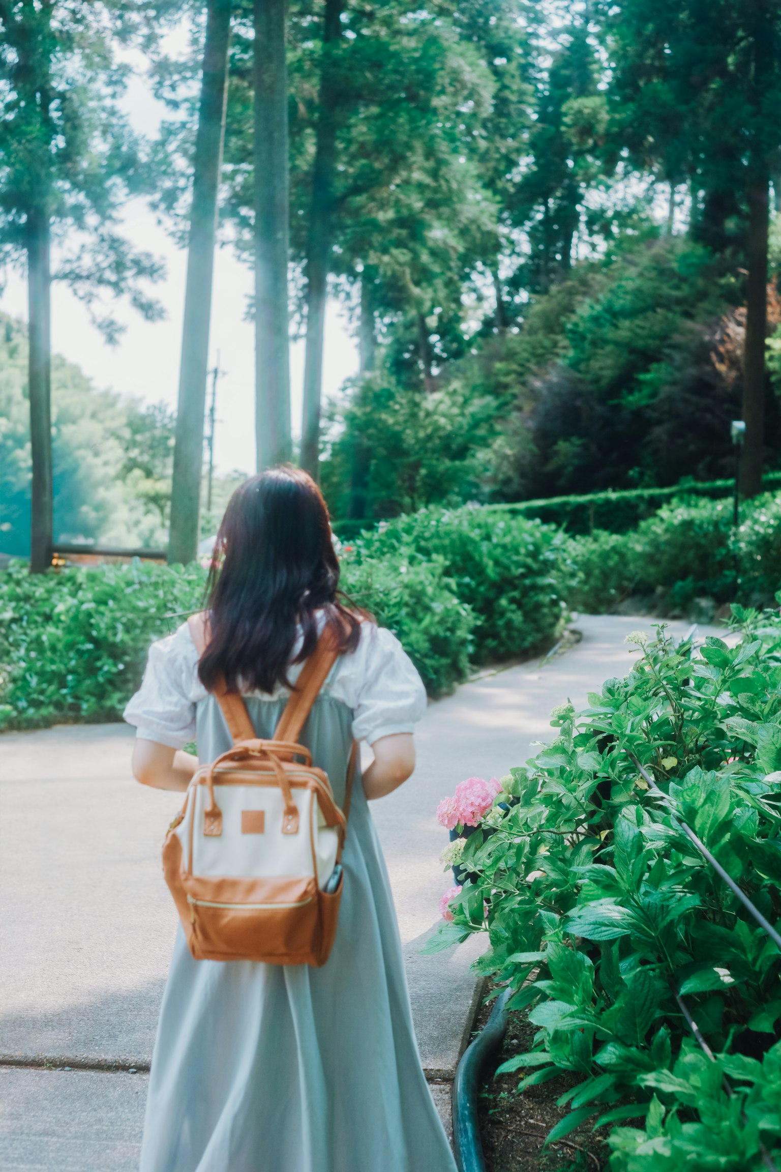 A woman walking along a green path with a backpack