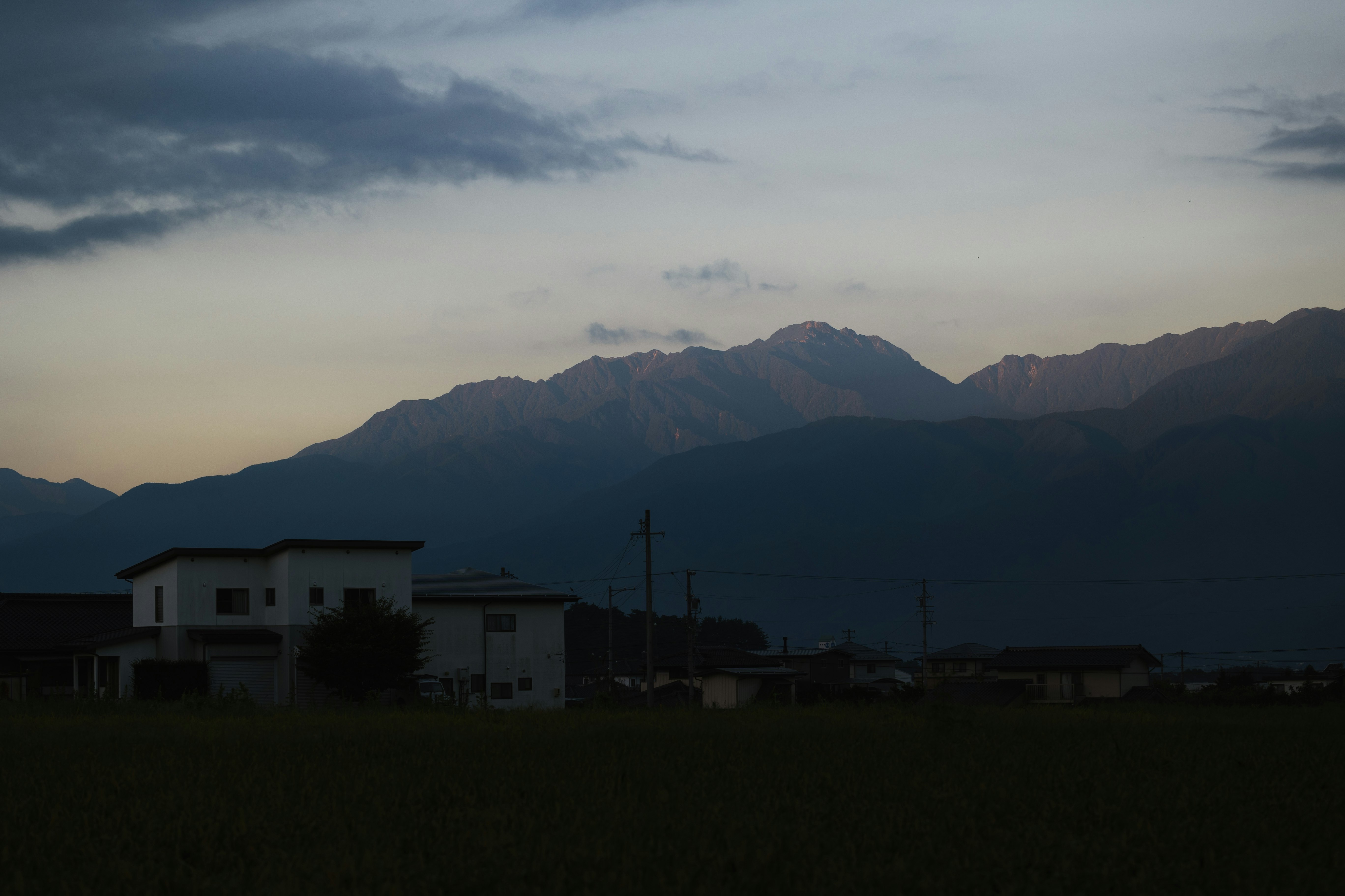 paysage rural au crépuscule avec vue sur une chaîne de montagnes