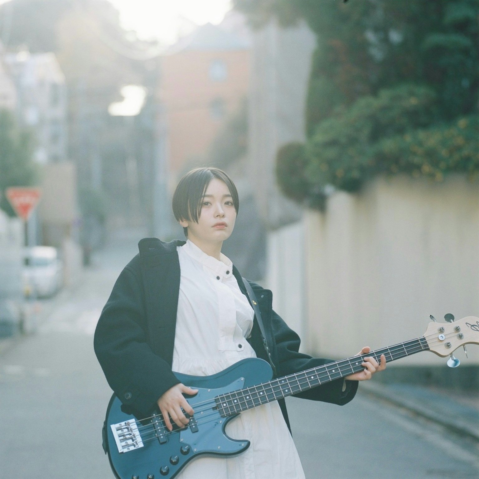 Donna che tiene una chitarra basso blu in una strada