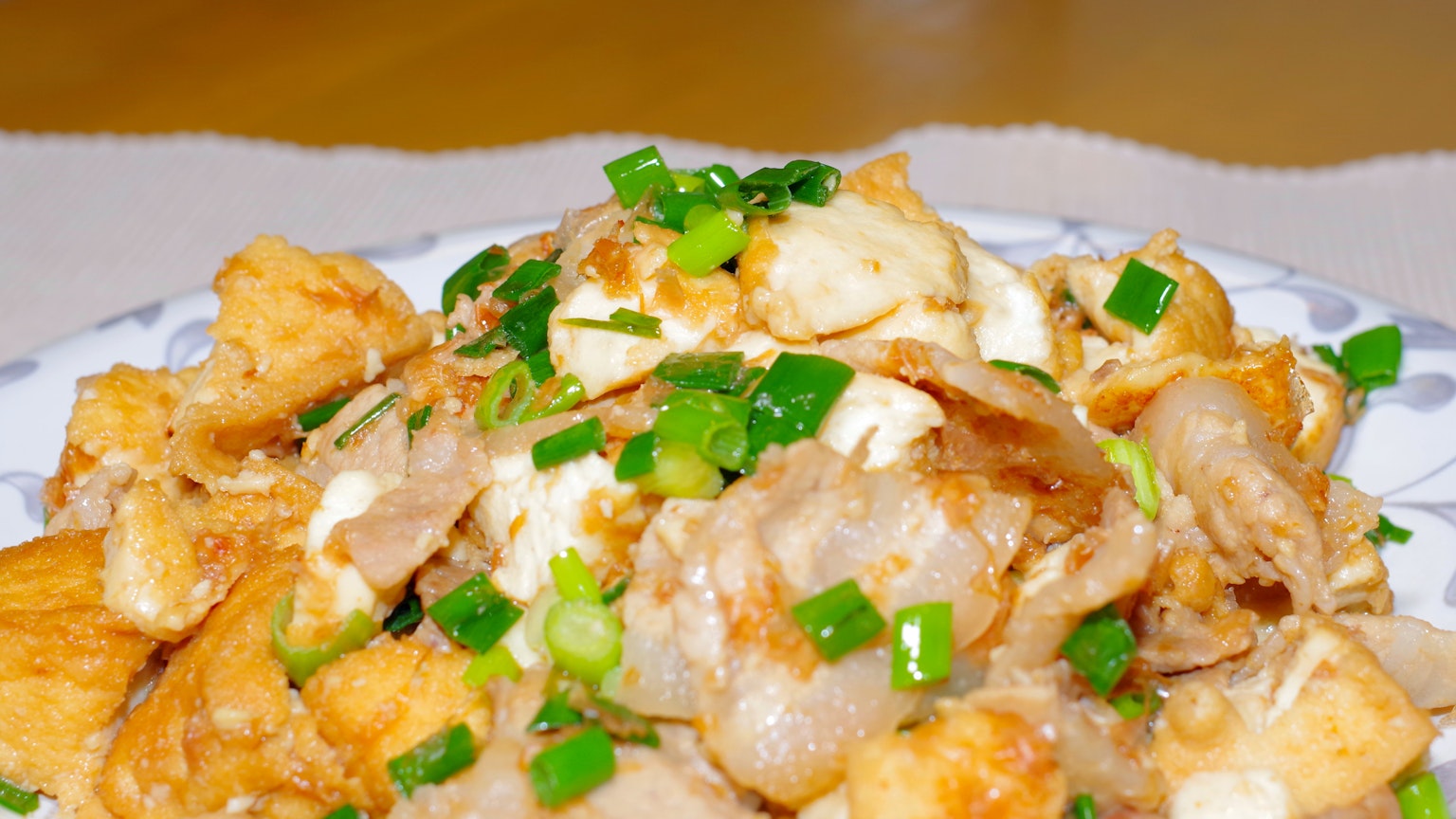 Un delizioso piatto di maiale saltato e tofu guarnito con cipollotti