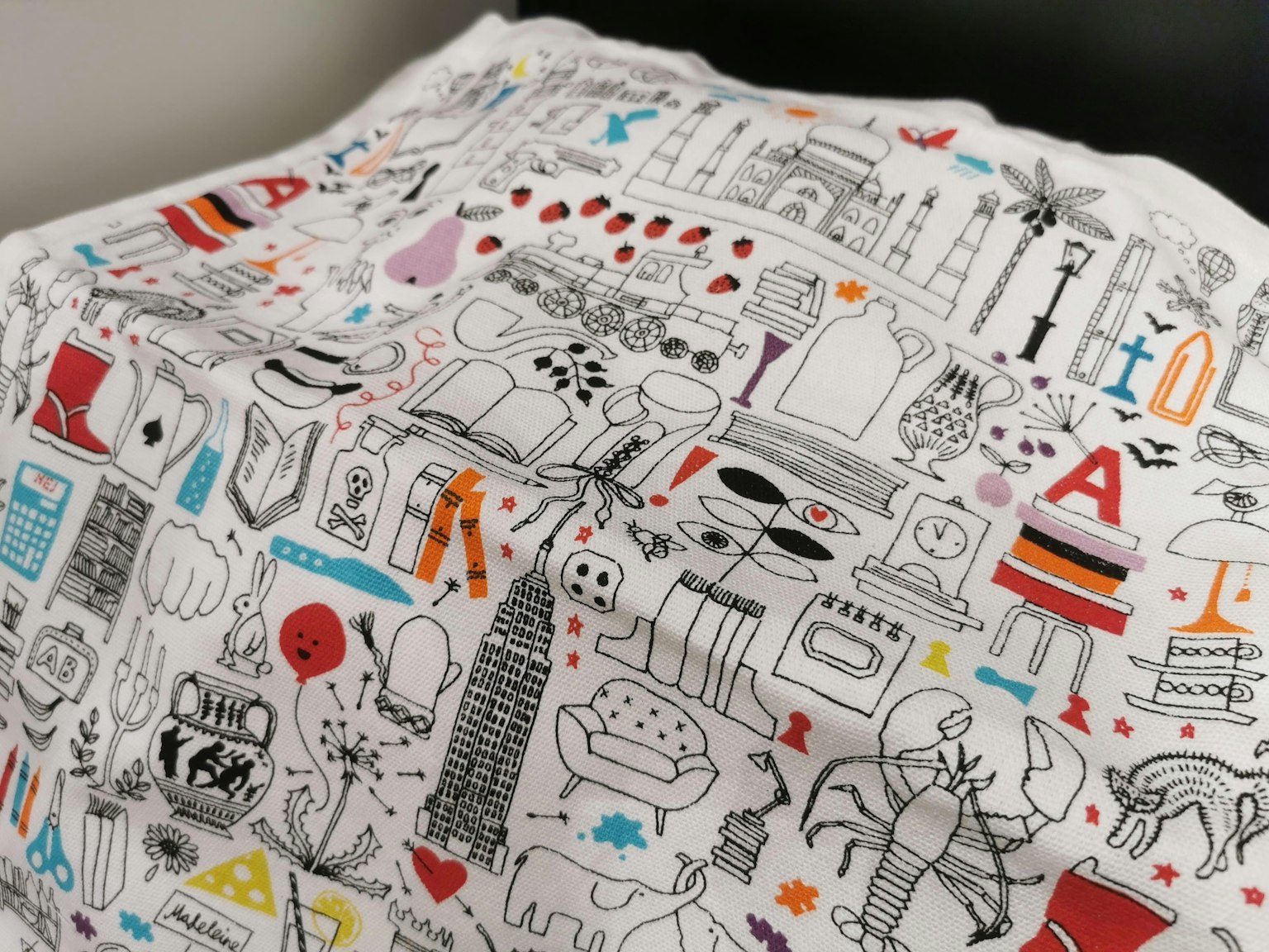 A white cushion featuring diverse illustrations and patterns