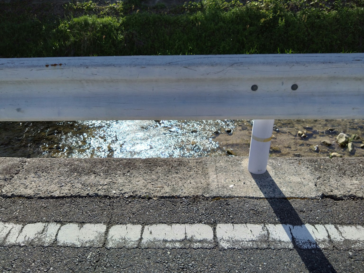 Roadside guardrail with glistening water surface