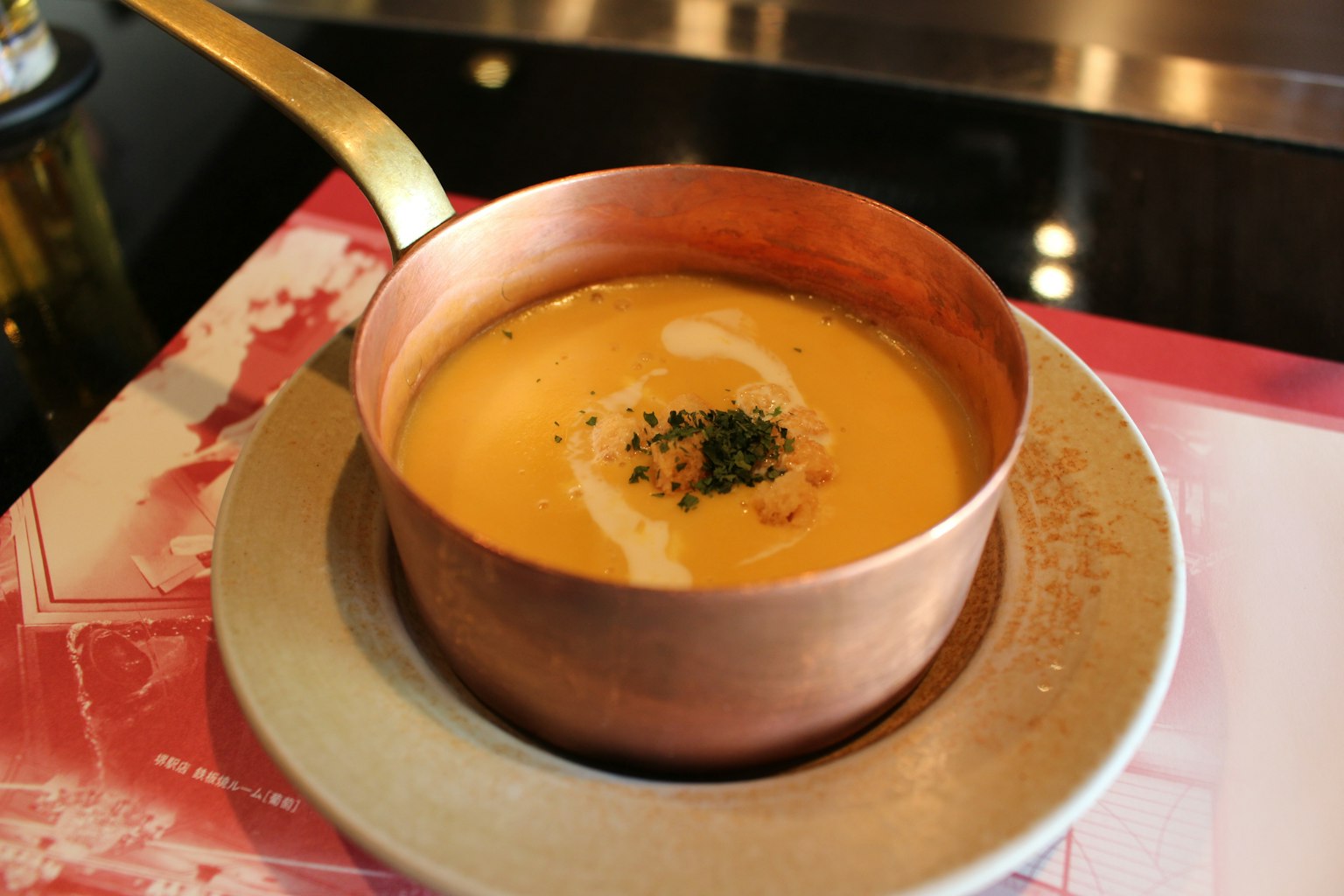Soupe crémeuse servie dans une casserole en métal avec garniture