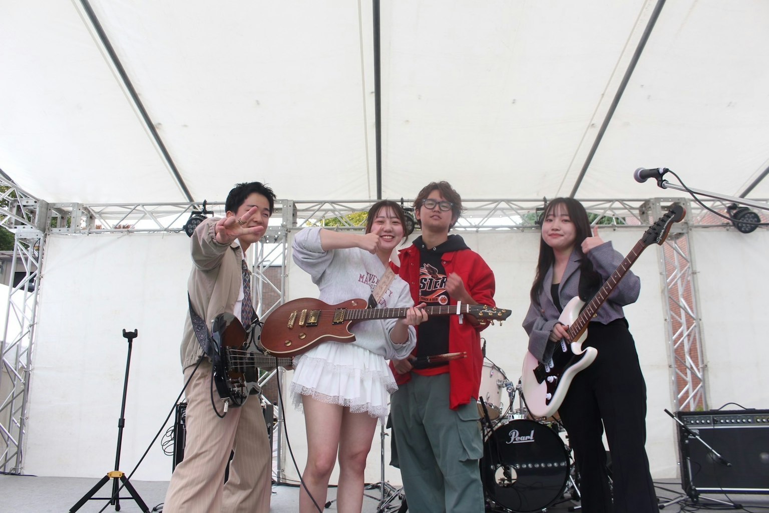 สมาชิกวงดนตรีโพสท่าบนเวทีพร้อมเครื่องดนตรี