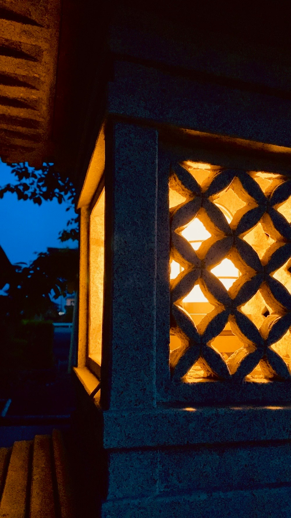 灯籠の格子模様が浮かぶ夜の神社の門