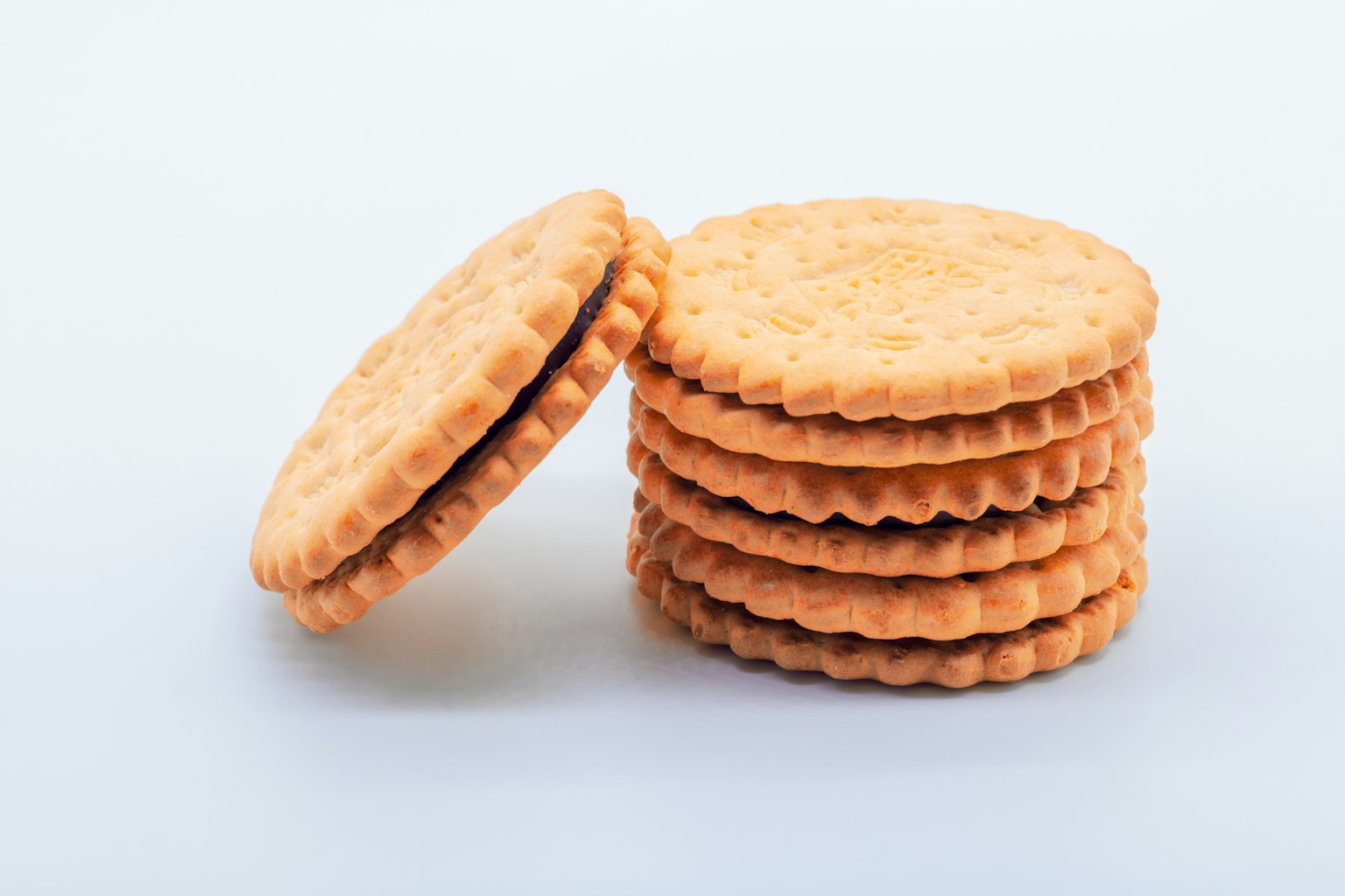 Stapel von orangefarbenen, mit Creme gefüllten Keksen auf weißem Hintergrund