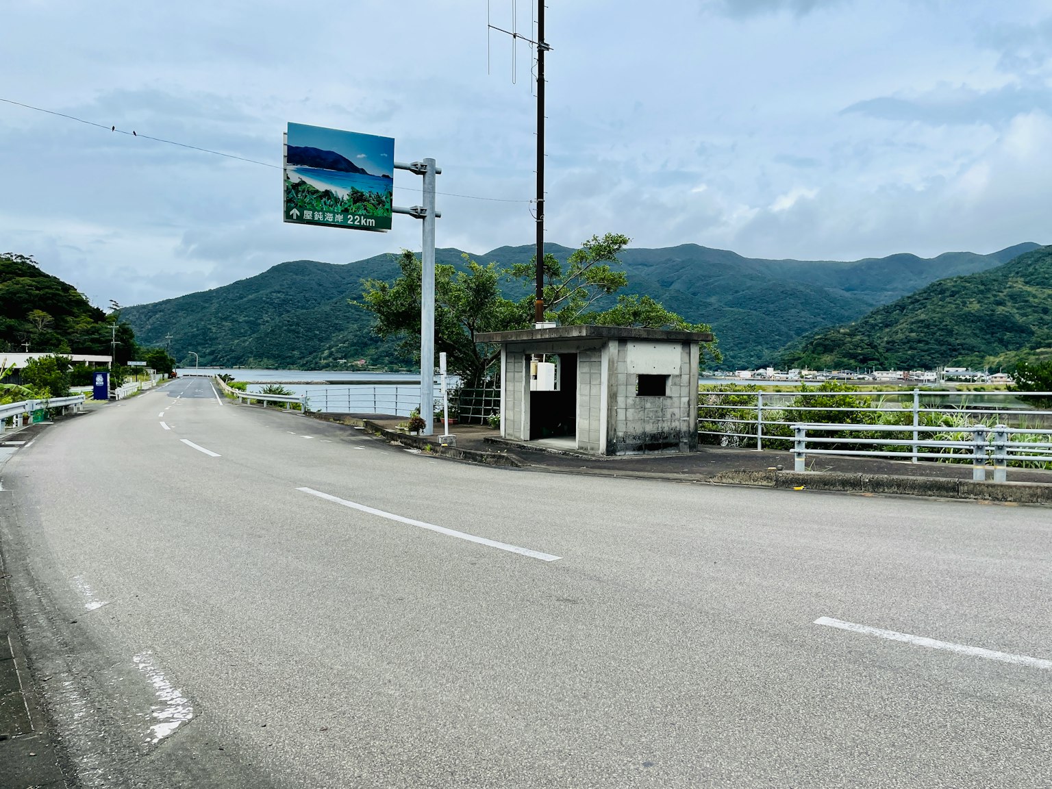 一座小建築位於寧靜的道路旁，背景是山的美景
