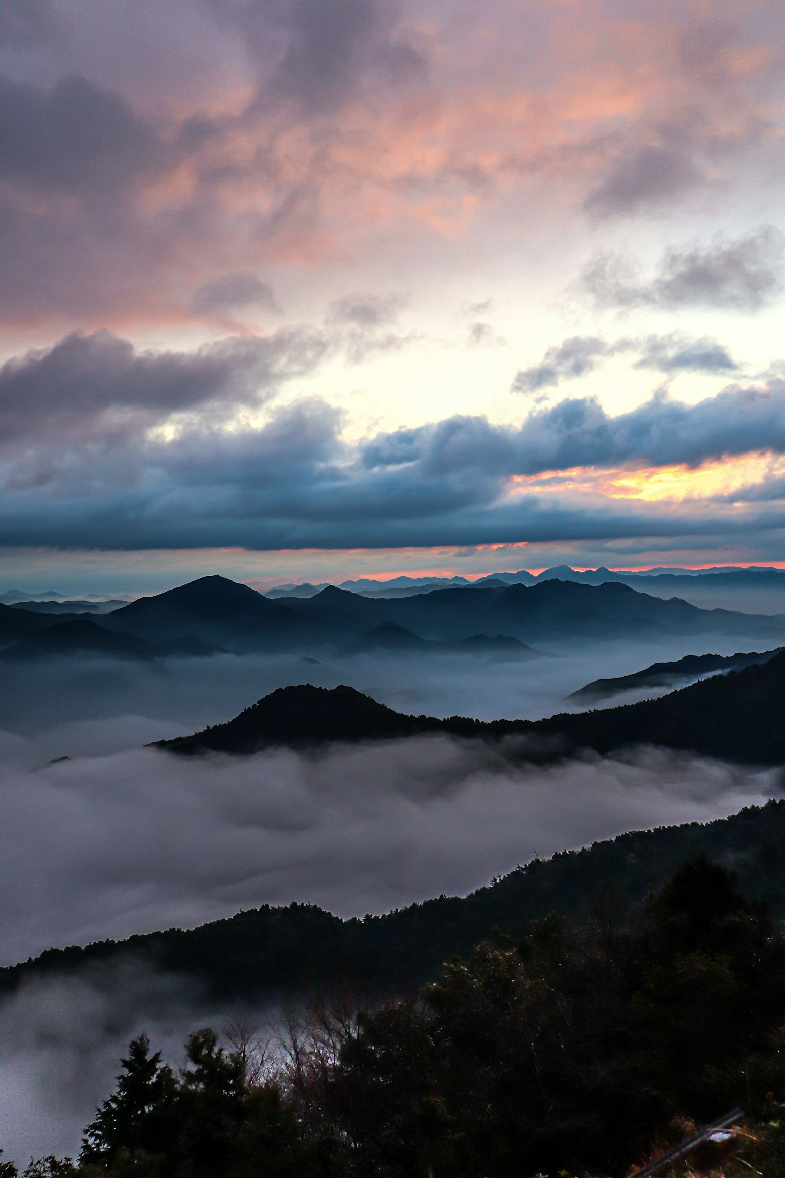 Scenic view of mist-covered mountains under a sunset sky