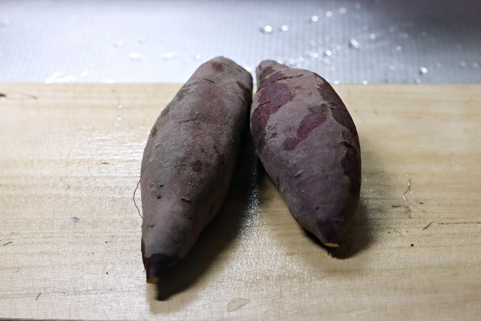Two sweet potatoes placed on a wooden board