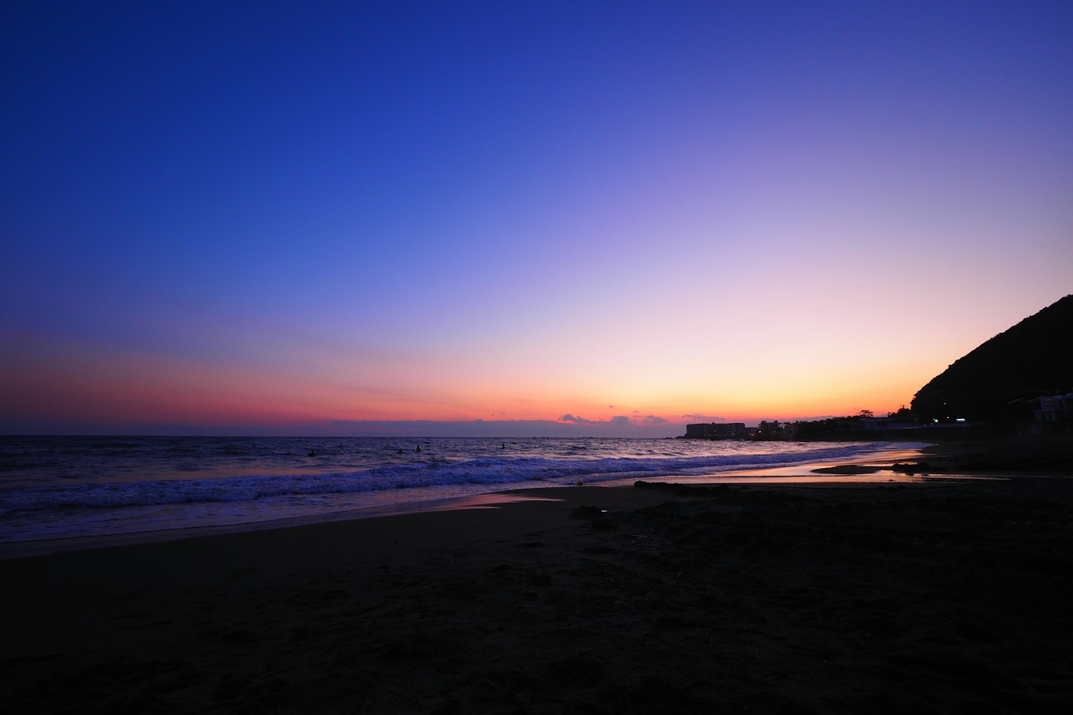 Belle vue de coucher de soleil côtier avec un ciel dégradé orange et violet vagues s'échouant sur le rivage