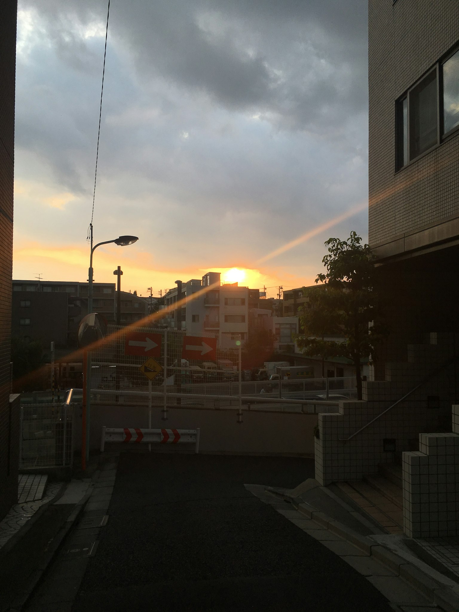 Städtische Szene mit Sonnenuntergang, der durch die Wolken schimmert